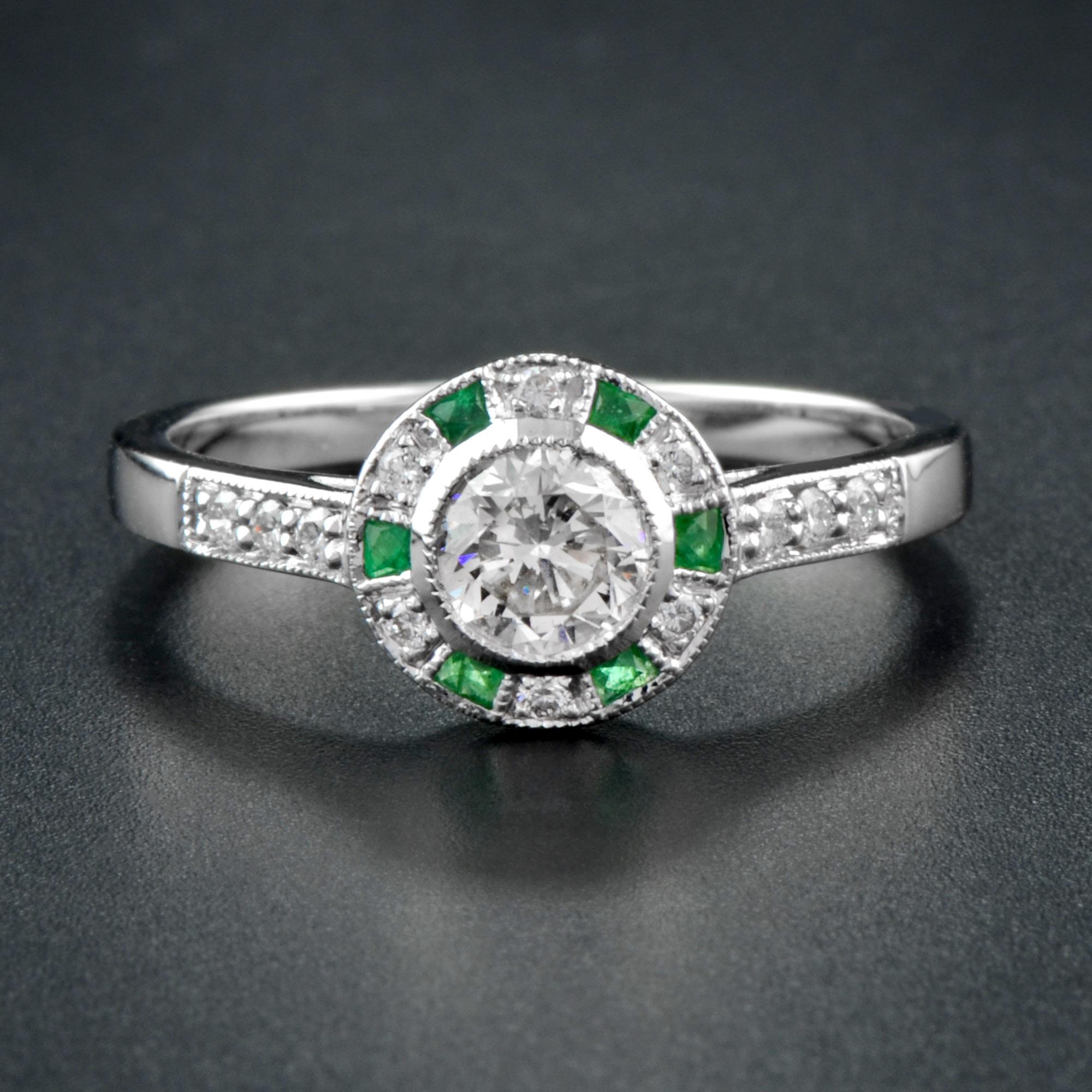 A stunning Art Deco design diamond and emerald target ring, centered with a beautiful round cut diamond setting surrounded by a frame of French cut emeralds and diamonds, all in a finely hand-crafted 18K white gold mount with plain band and diamonds