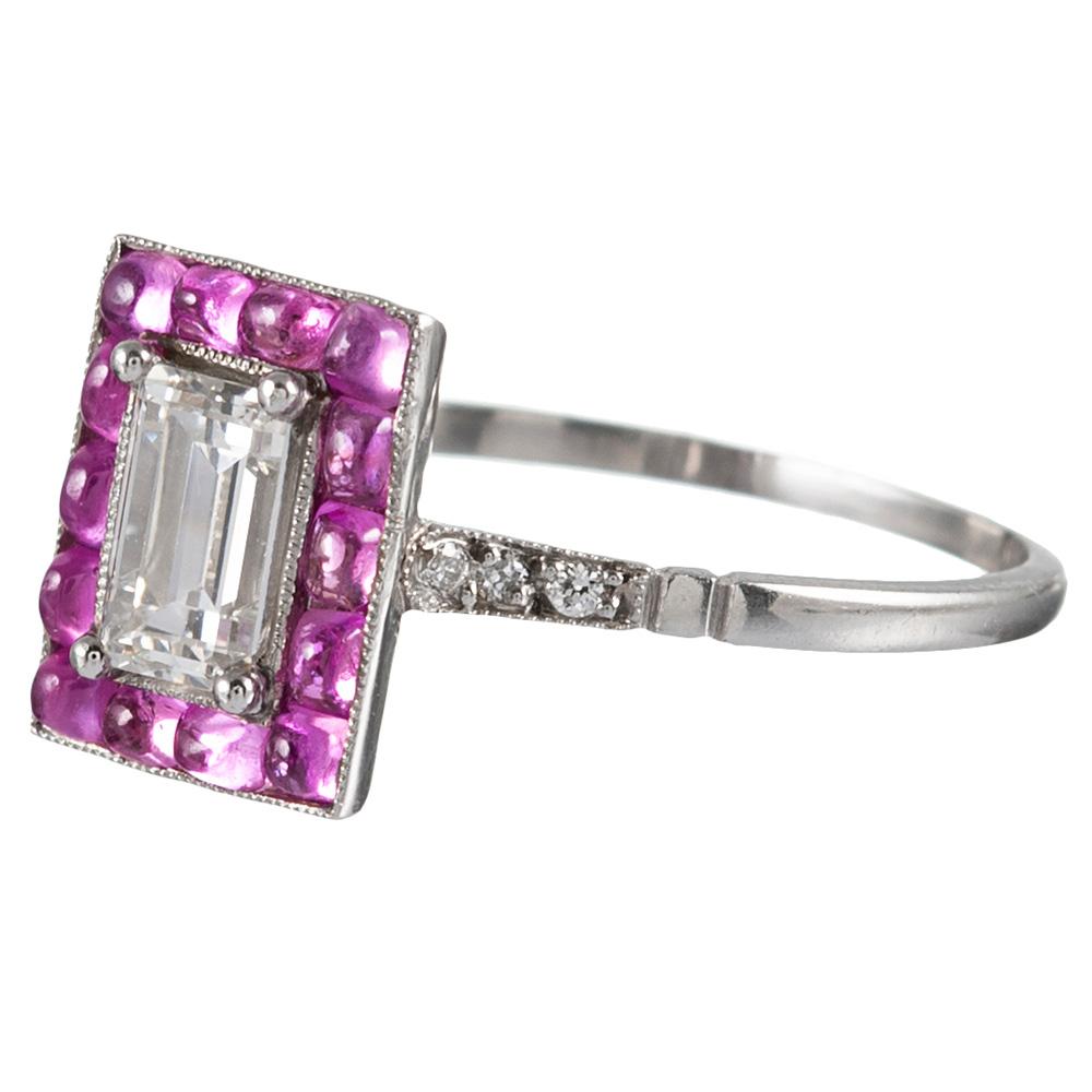 The design of this ring is inspired by the classic creations from the Art Deco period, yet the piece is of newer manufacture. Hand made in platinum, the centerpiece is a .71 carat emerald cut diamond gleaming from its millgrain-edged bezel setting.