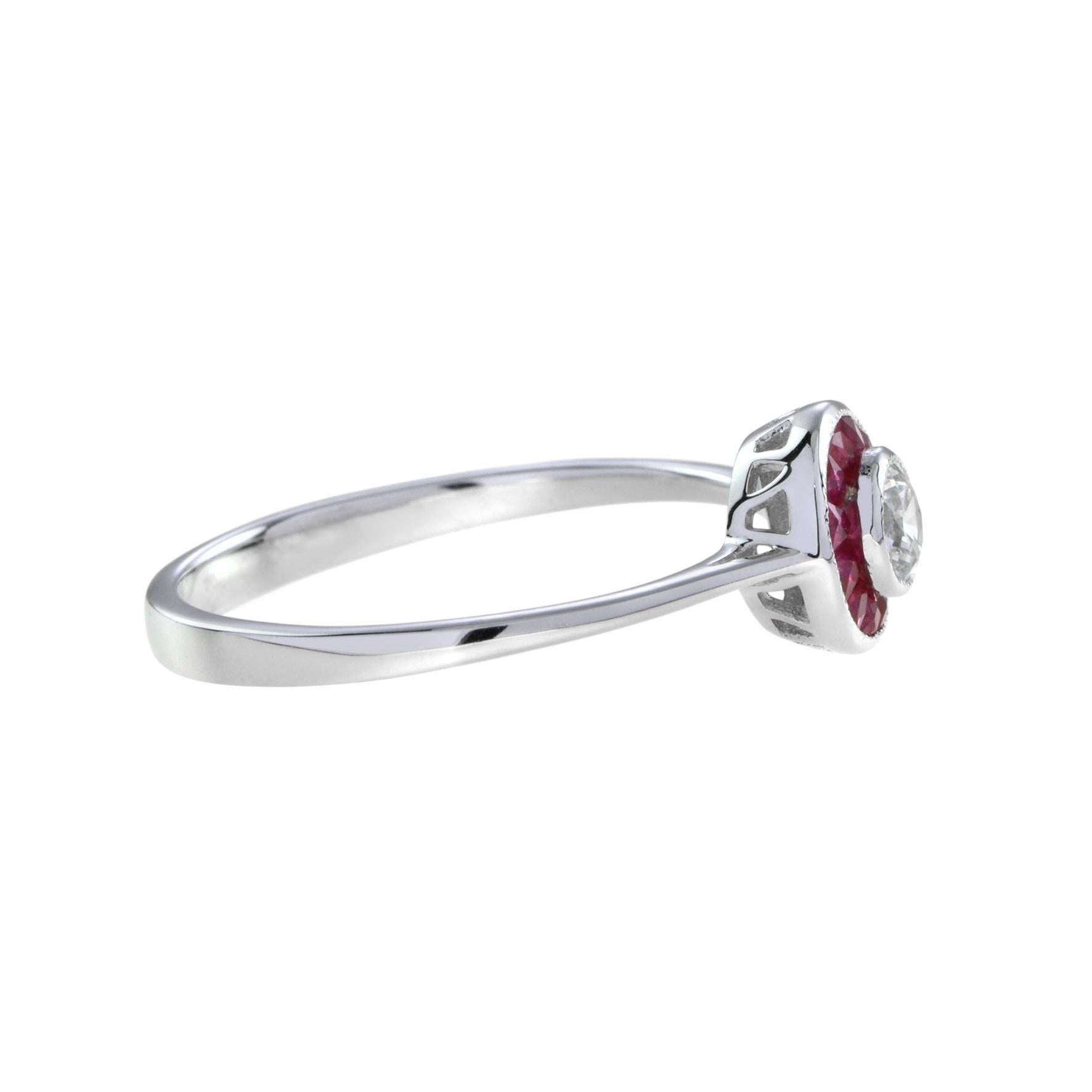A diamond and ruby target ring, rub-over-set to the center with a round brilliant cut diamond surrounded by French cut rubies. A gorgeous diamond and ruby target ring, made in the style of Art Deco ring. 14K White Gold. 
Ring Information
Style: Art