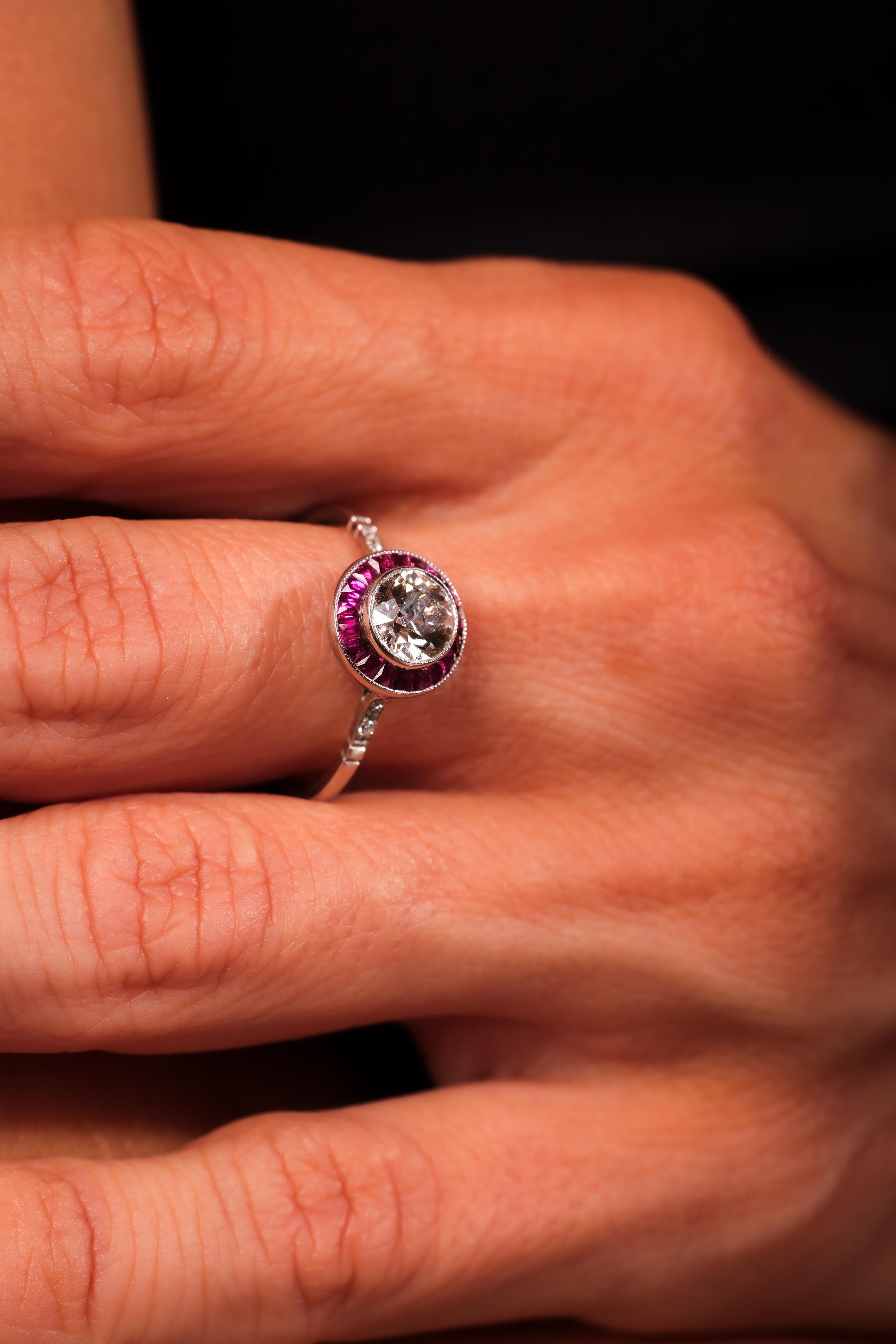 Mittelstein: Diamant im alten europäischen Schliff
Gewicht: .78 Karat
Farbe: M-N
Klarheit: SI2
Akzentuierungsstein: 6 Diamanten aus alter Mine
Gewicht: Ungefähr .03 Karat
Farbe: H
Klarheit: VS
Akzentuierungsstein: 18 rote Rubine im