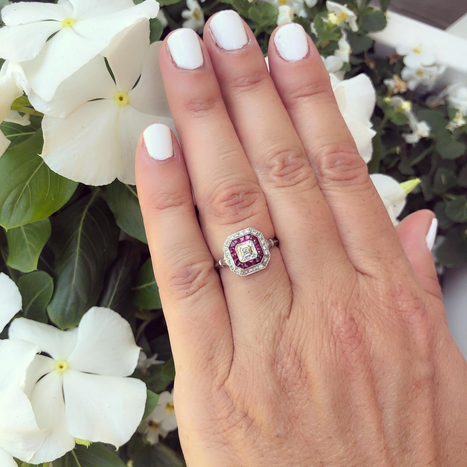 Art Deco inspired, this 18k white gold ring is a true showstopper! Centering an Asscher-cut diamond weighing approximately 0.55-ct., H-I-J/VS quality, framed by a row of channel-set calibre-cut rubies and an outer frame of 24 round brilliant-cut