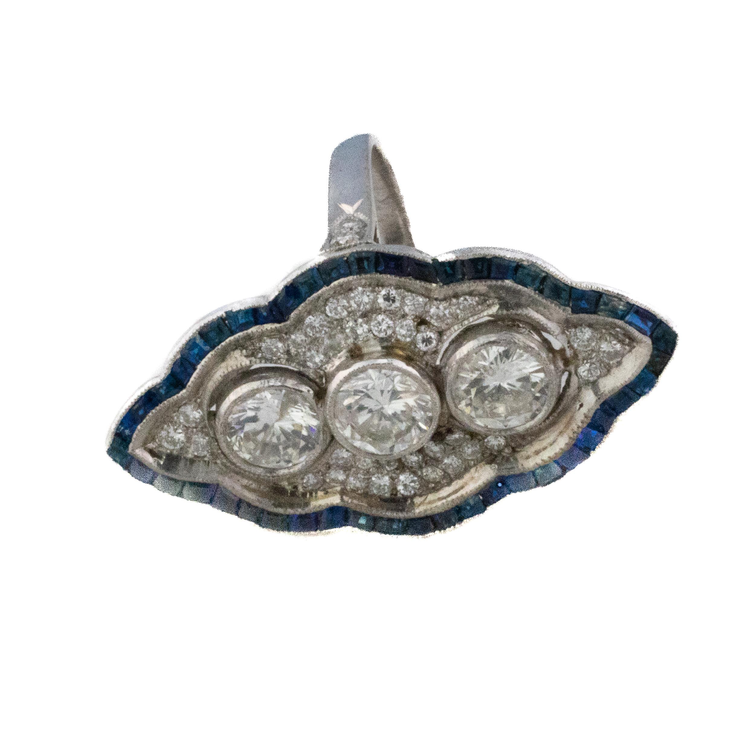 Bague de style Art déco avec diamant et saphir en forme de navette

Description : Cette bague frappante en or blanc 18 carats présente une silhouette de navette classique centrée par trois diamants ronds sertis verticalement, chacun encadré dans des