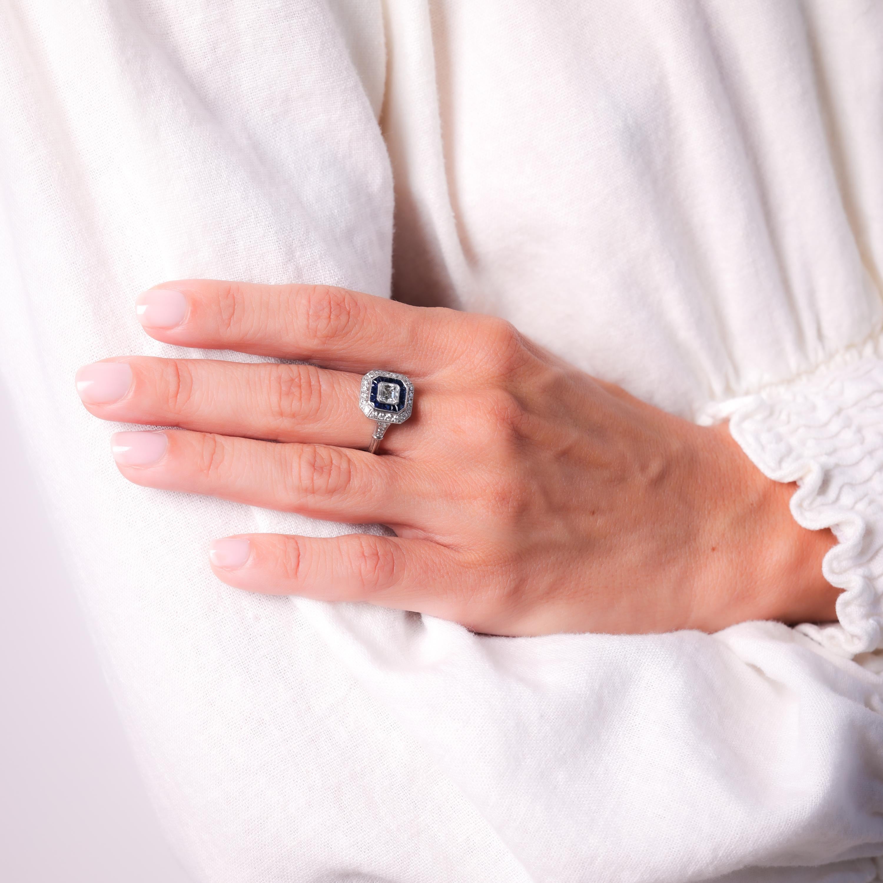 Center Stone: Asscher Cut Diamond 
Weight: Approximately .55 Carat
Color: H
Clarity: VS
Accent Stone: 20 Calibre French Cut Blue Sapphires
Weight: Approximately .80 Carats
Accent Stone: 24 Old European Cut Diamonds
Weight: Approximately .50