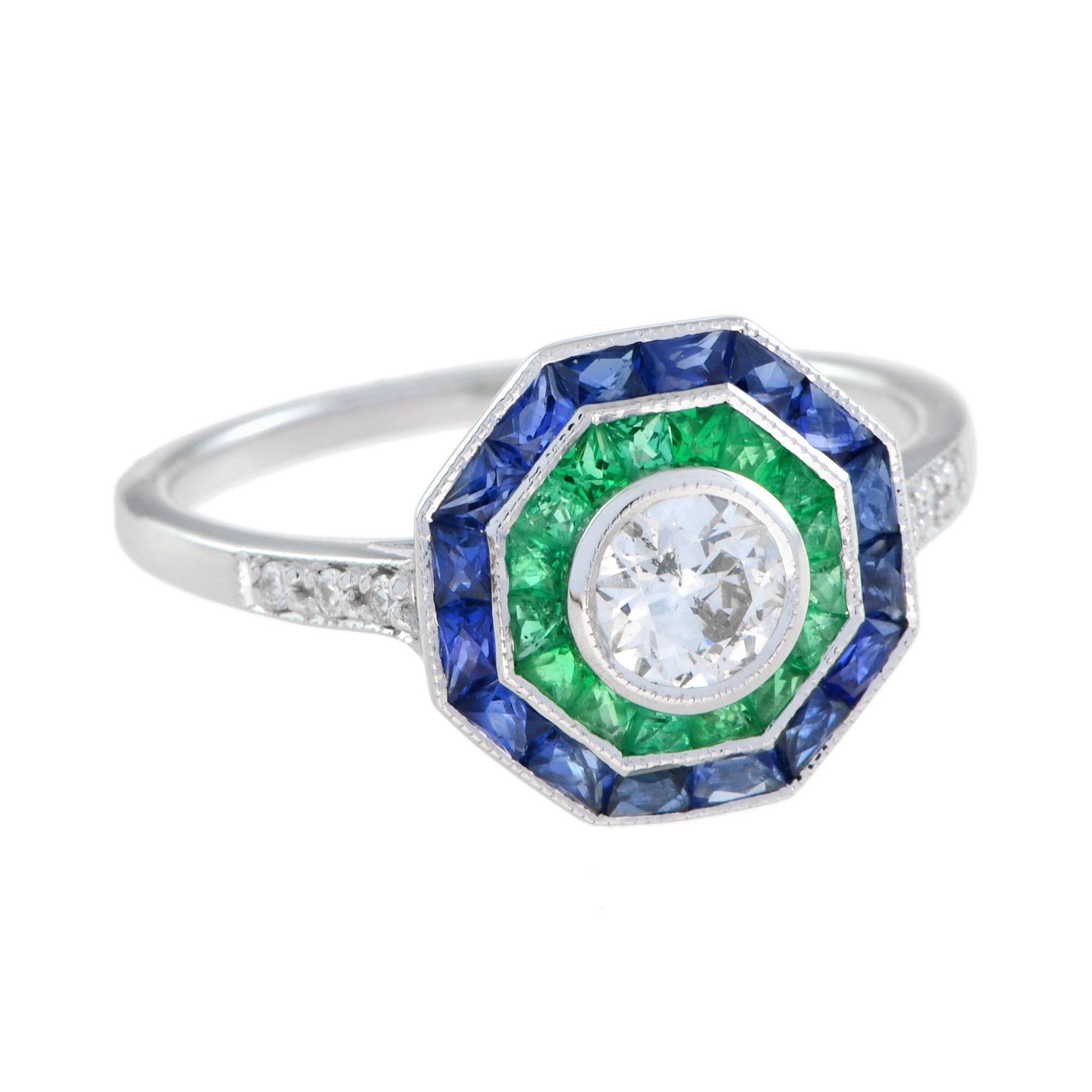 Cette bague de style Art déco est sertie d'un double halo de pierres précieuses - saphir bleu et émeraude - autour d'un diamant central de taille ancienne. Les diamants sont brillants et présentent un excellent éclat, tandis que le saphir et