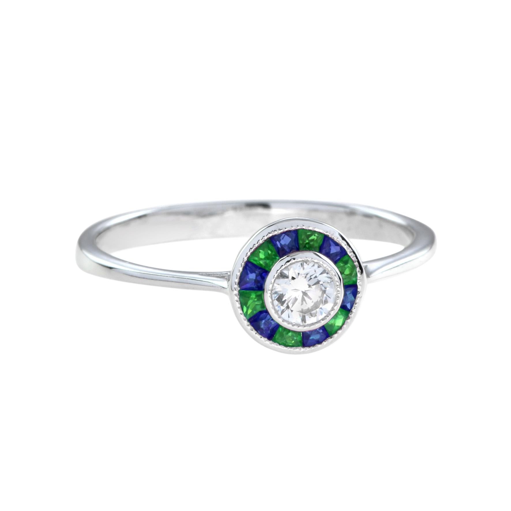 Anillo blanco de diamantes con esmeraldas y zafiros, engastado al centro con un diamante redondo de talla brillante rodeado de esmeraldas y zafiros de talla francesa, todo engastado en oro blanco de 18 quilates. Un precioso anillo blanco de