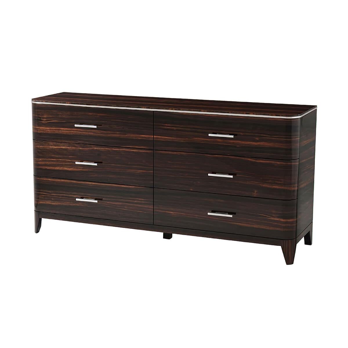 An Art Deco style dresser inspired by 1930s luxury. This six drawer dresser with a rounded edge top with polished nickel trim, exotic Amara veneers with polished nickel finish handles, on tapering legs, with soft closing drawers.

Dimensions: 70