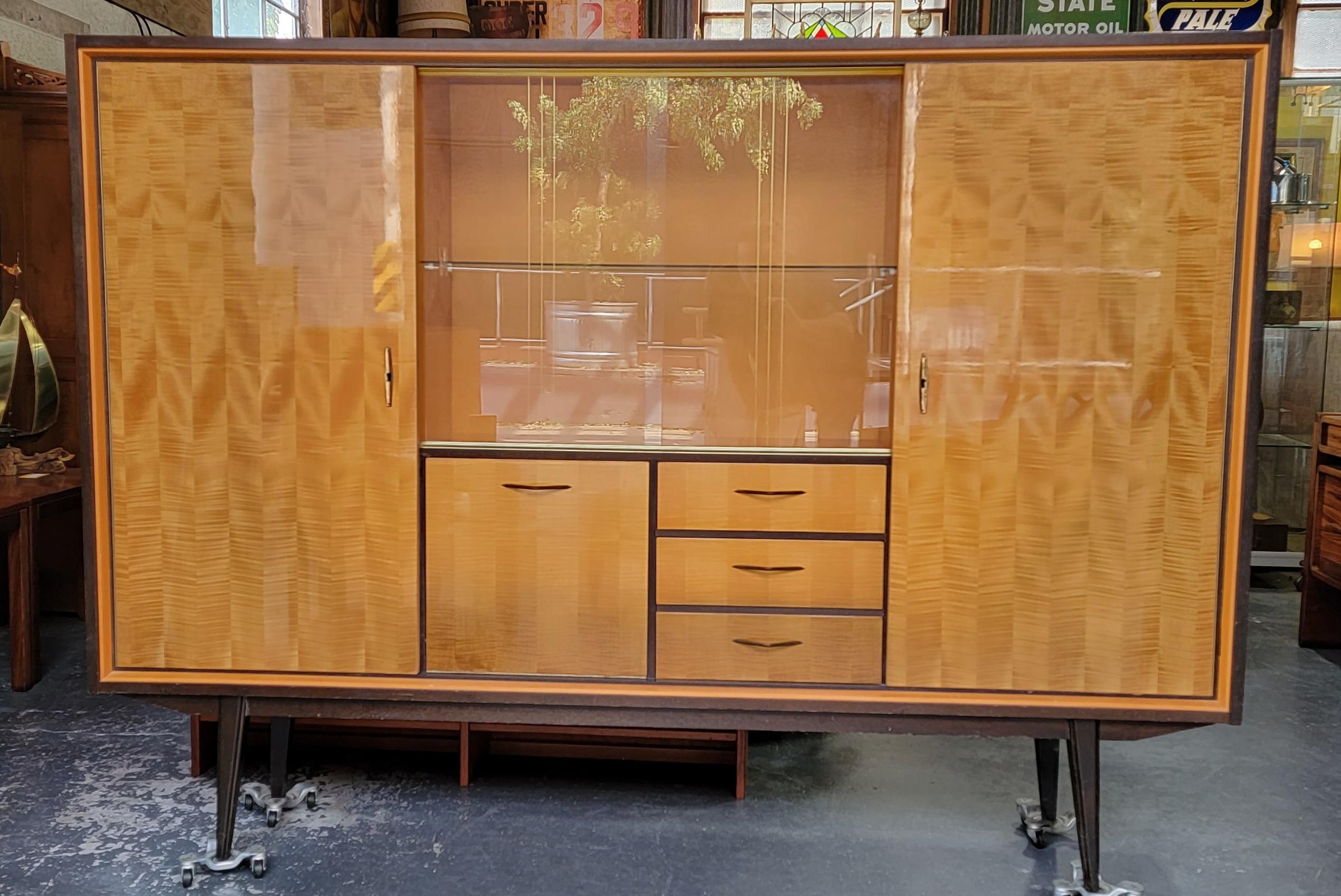 Extraordinary Large-Scale dry bar storage cabinet. Exotic wood grain doors, ribbon cut mahogany interior. Sliding glass doors for display, cabinet doors for hidden storage. Flip down door with decorative mirrored dry bar. It was difficult to