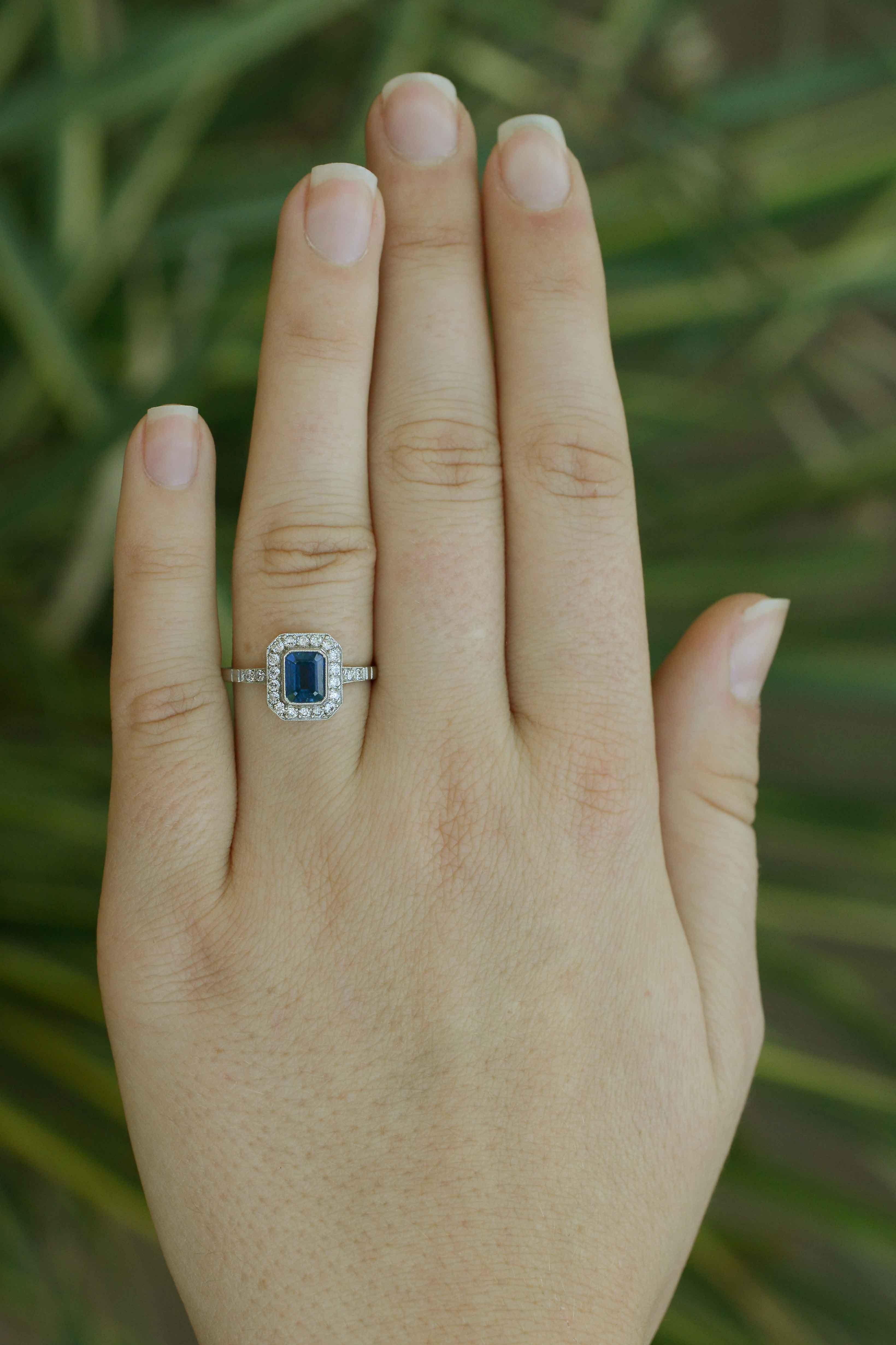 A decadent and intriguing Art Deco revival sapphire and diamond engagement ring. Floating in a pool of diamonds is a rich, cornflower blue emerald cut sapphire in a dainty millegrained bezel. We love the octagon halo exhibiting strong Art Deco
