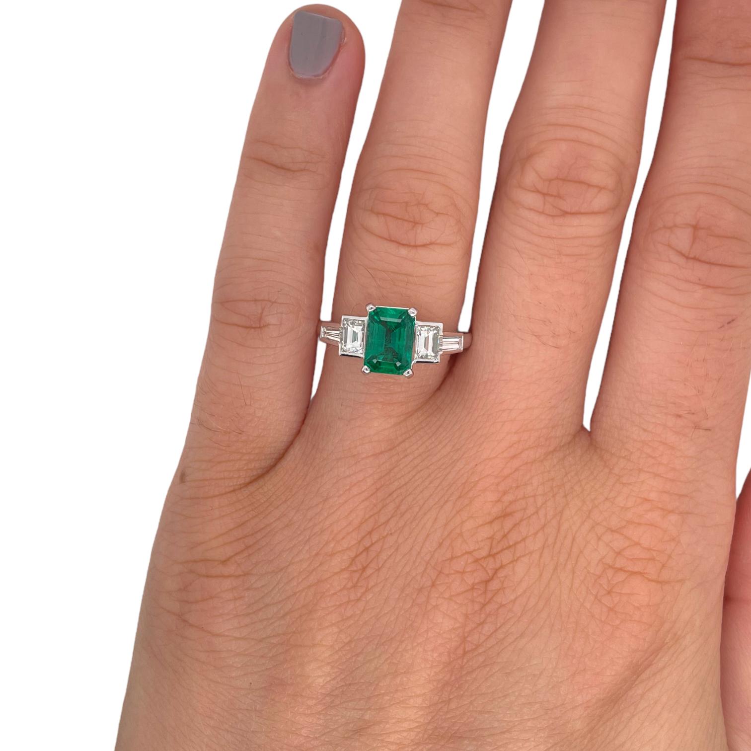 Ring contains one center emerald shape emerald 1.25ct, two straight baguette diamonds and two tapered baguettes, 0.78tcw. Diamonds are G in color and VS2 in clarity. Center stone is mounted in a handmade basket prong setting and side diamonds are
