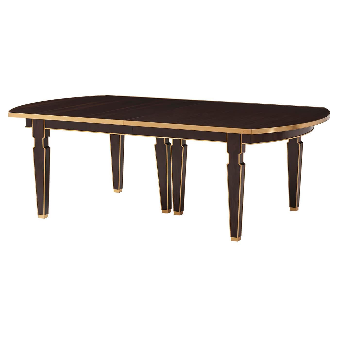 An Art Deco style extension dining table with a historic classic Silhouette. The rectangular dining table with curved ends and a brass-bound apron. Set on slatted baluster legs trimmed and outlined in gilt. 

Open dimensions: 162