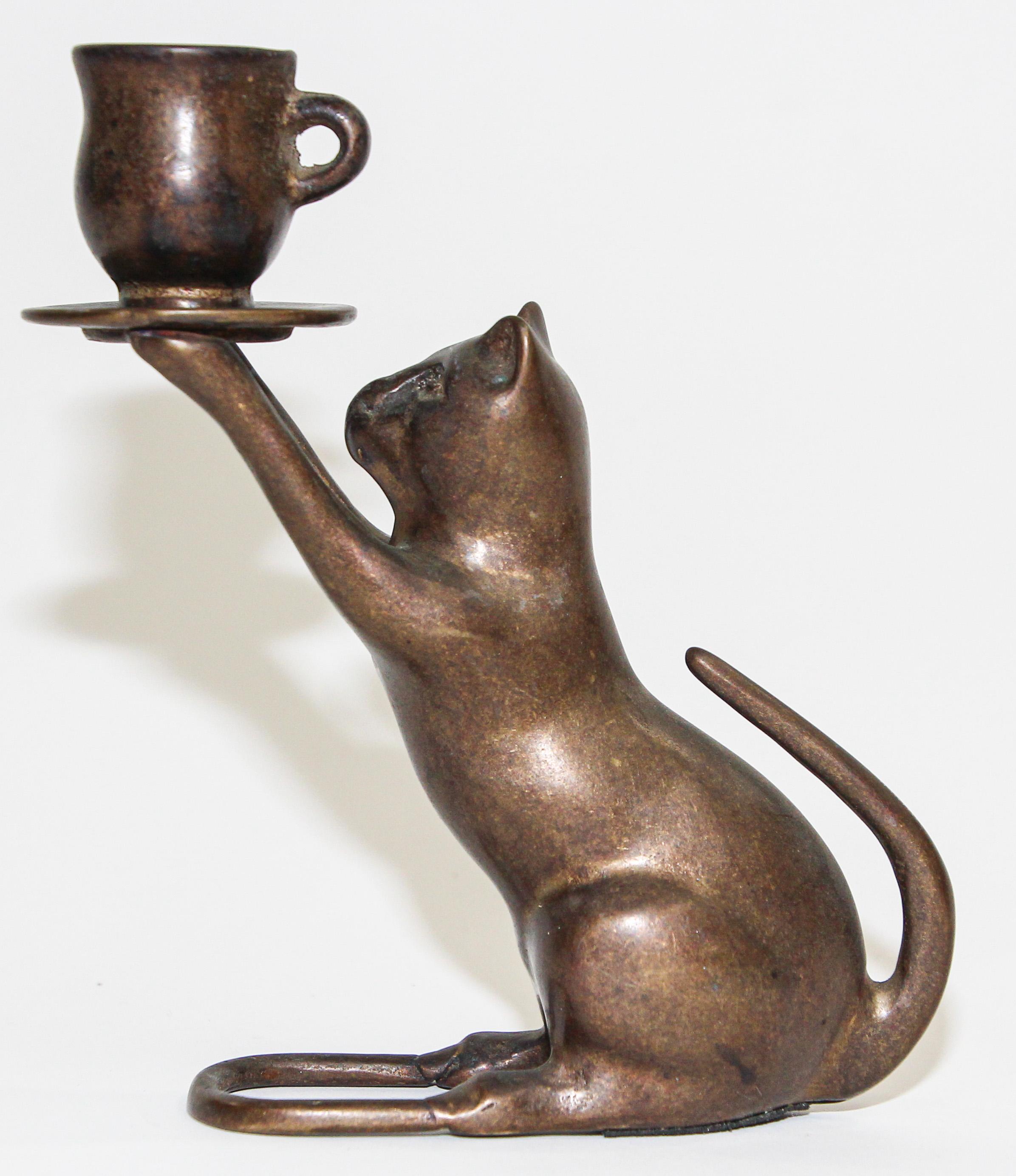 Small Art Deco style French bronze candle holder animal cat sculpture.
Patinated bronze candle holder in the style of Egyptian Revival figure of a standing cat holding a a cup candle holder
Small French bronze candle holder in the form of a cat