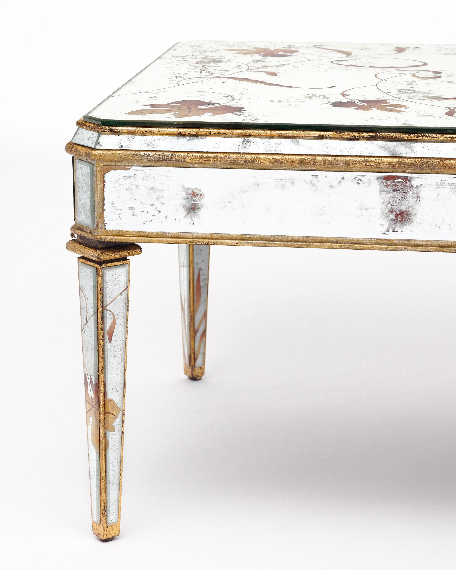 Table basse de France de style Art Déco. Cette table est entièrement plaquée de miroir et présente de remarquables détails églomisés. L'églomisation est un terme français désignant une technique qui consiste à appliquer des décorations et des