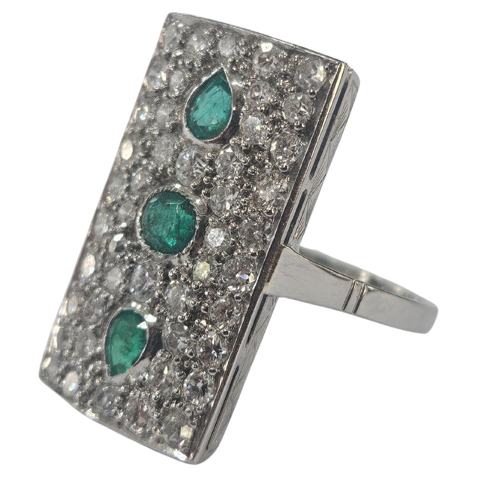 Fantastique bague française Art déco tardif, 1940-1950 en or blanc 18 carats. Galerie et beaux détails rectilignes gravés au burin.
3 Émeraudes ovales et en poire Total 0,45 cts. AA+
46 Diamants simples, suisses et taille brillant.  Total diamant