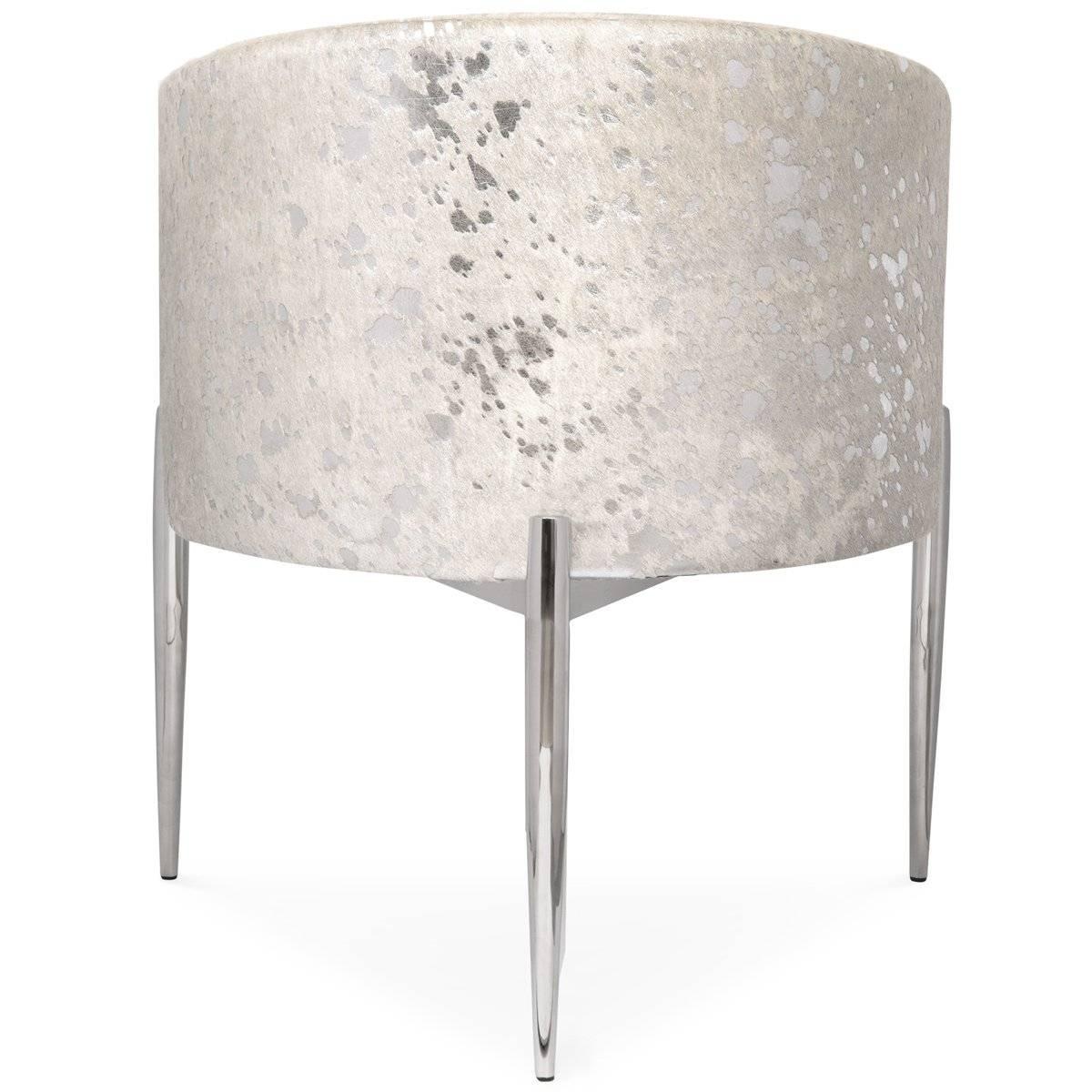 The Art Deco dining chair in silver speckled cowhide. This sophisticated and unique seat sits staunchly over a chrome three-leg base and remains true to the Art Deco theme by offering a curvilinear shape and a sharp outline. A perfect way to add a