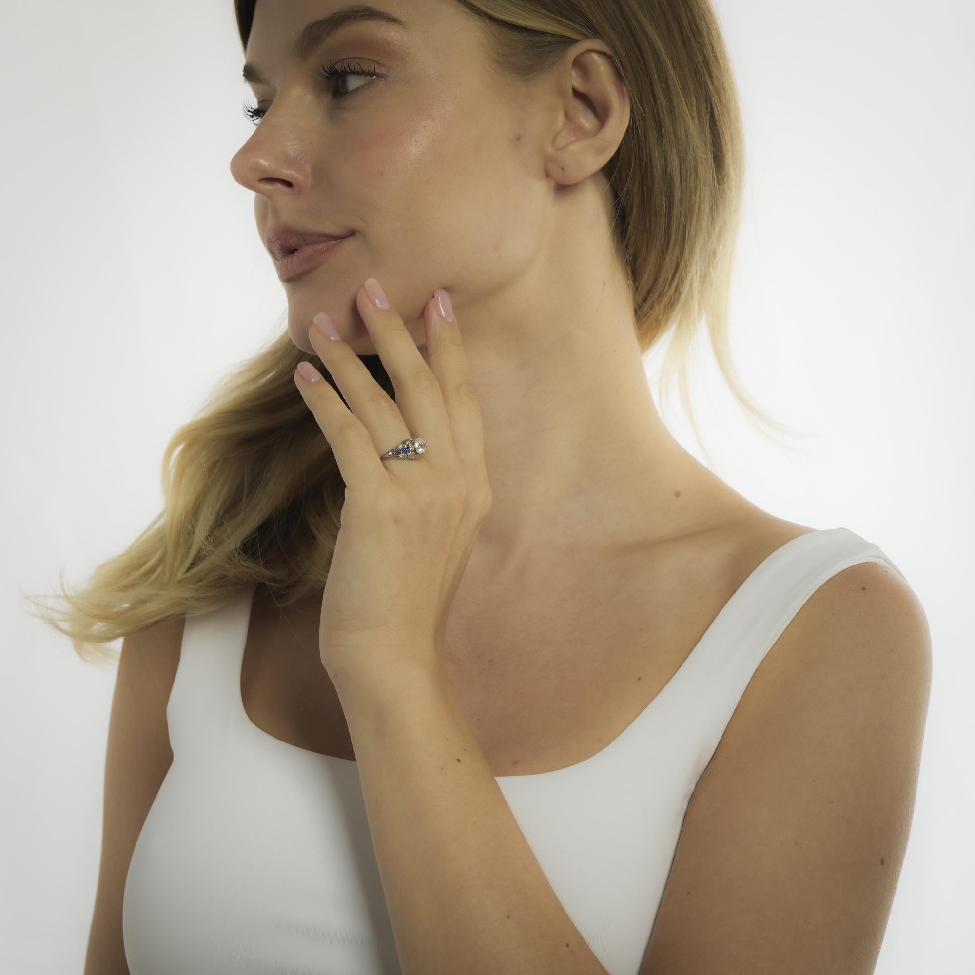 This platinum Art Deco style ring centers on a .98 carat GIA-certified old European cut diamond, framed by French cut sapphires and brilliant diamond accents for timeless elegance.
