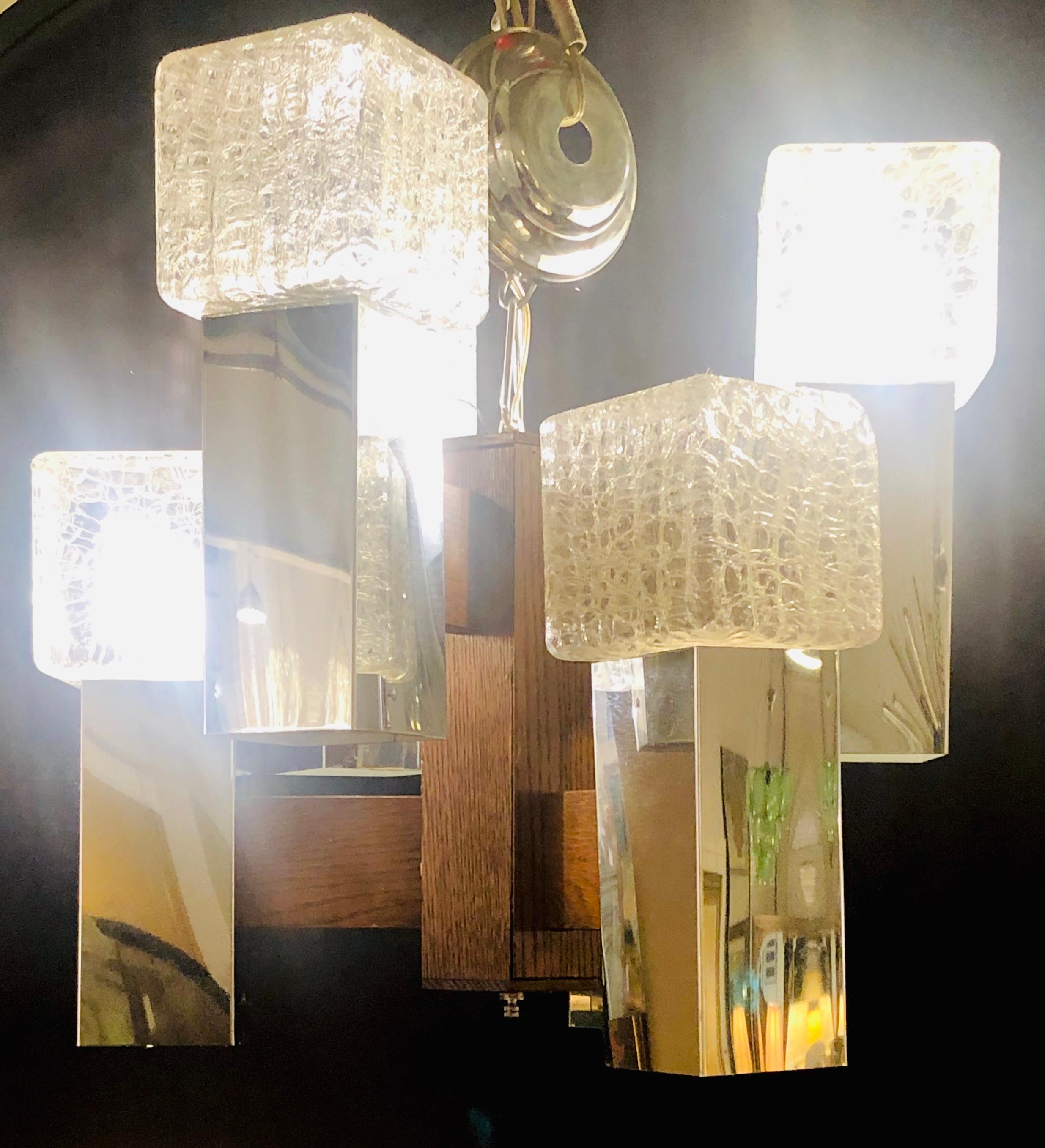 Lampadario in vetro e legno di radica in stile Art Déco con 12 luci e 2 livelli. I cubi di vetro crepato in scatola su piedistalli cromati. 

Lia