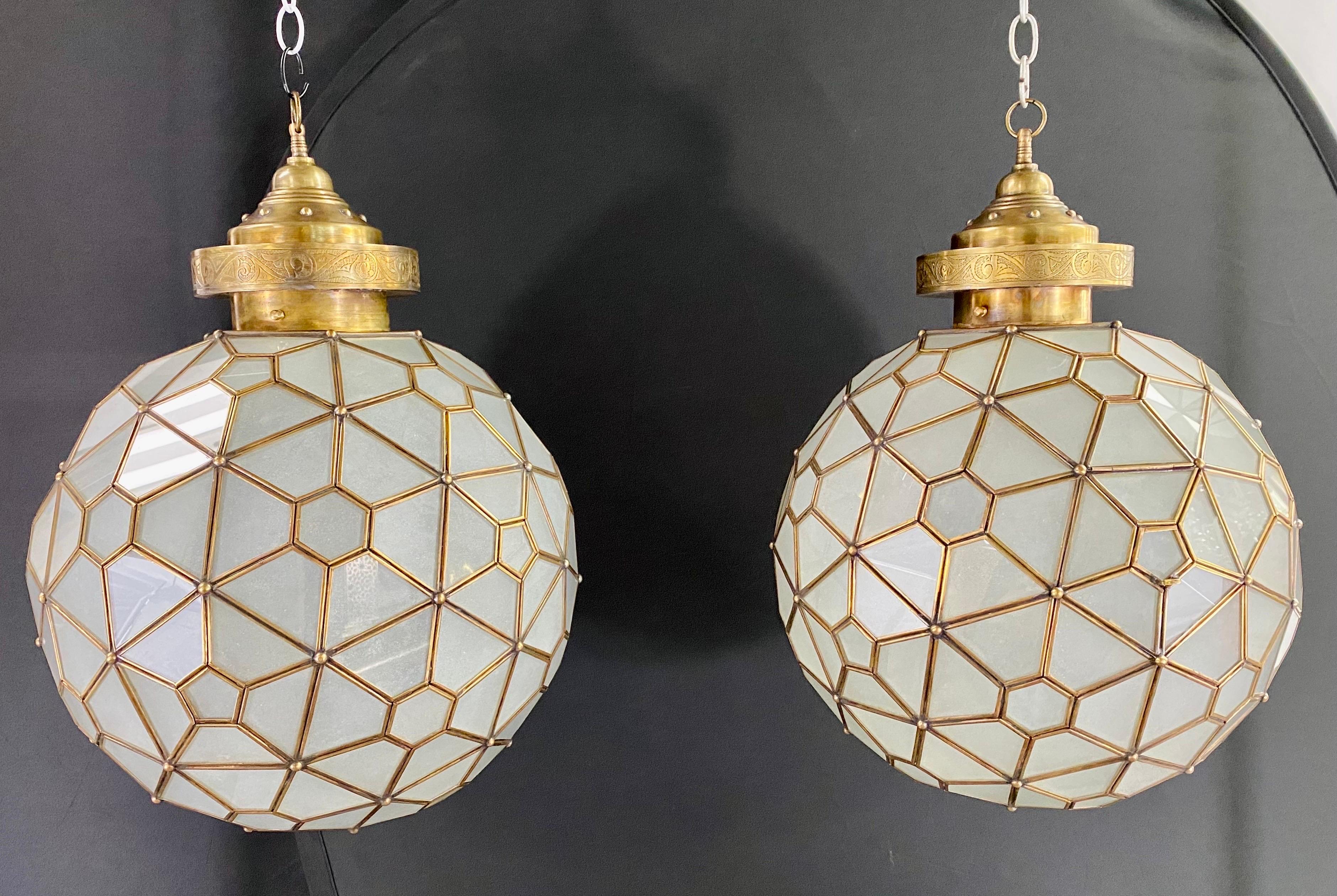 A pair of Art Deco style milk glass globe shape chandeliers, pendants or lanterns with brass inlay and handcrafted with a filigree design canopy. The stunning pendants are handmade using high quality brass and milk sanded glass and feature hexagonal
