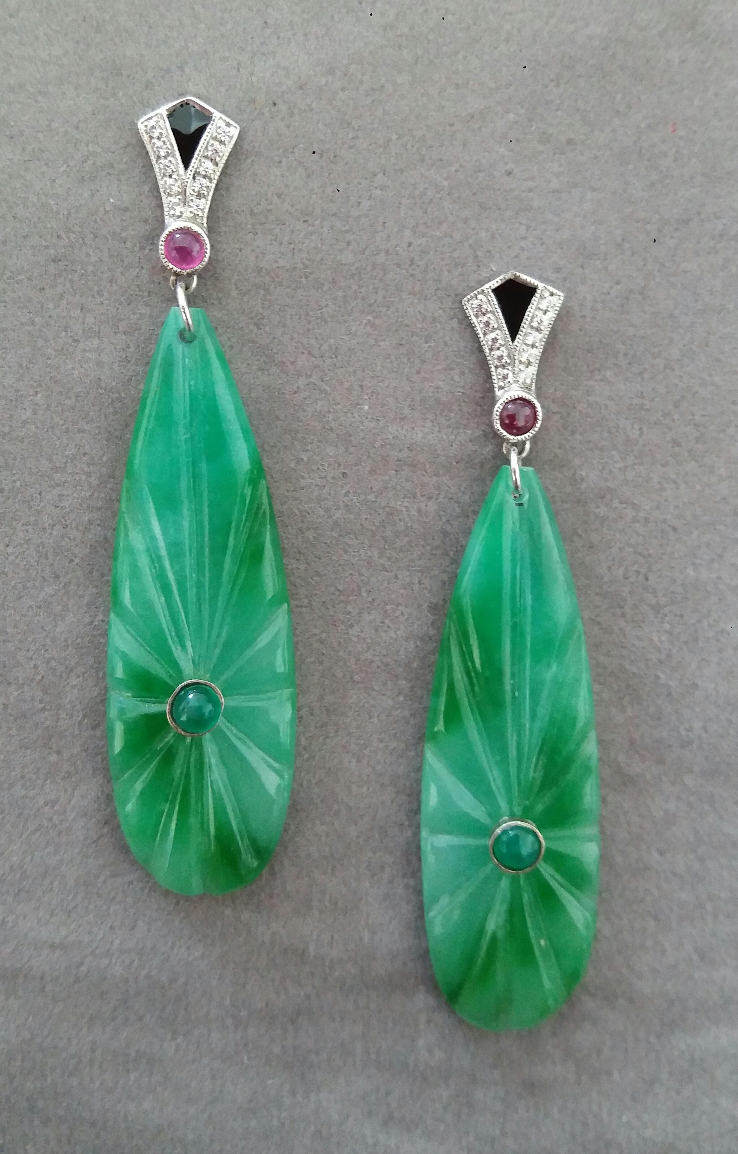 In these classic Art Deco Style earrings the tops are 2 parts  in 14 kt.white gold, 20 round full cut diamonds,small round ruby cabs and black enamel ,in the lower parts we have 2 Burma Jade engraved  drops measuring 15 x 41 mm with 2 small emeralds