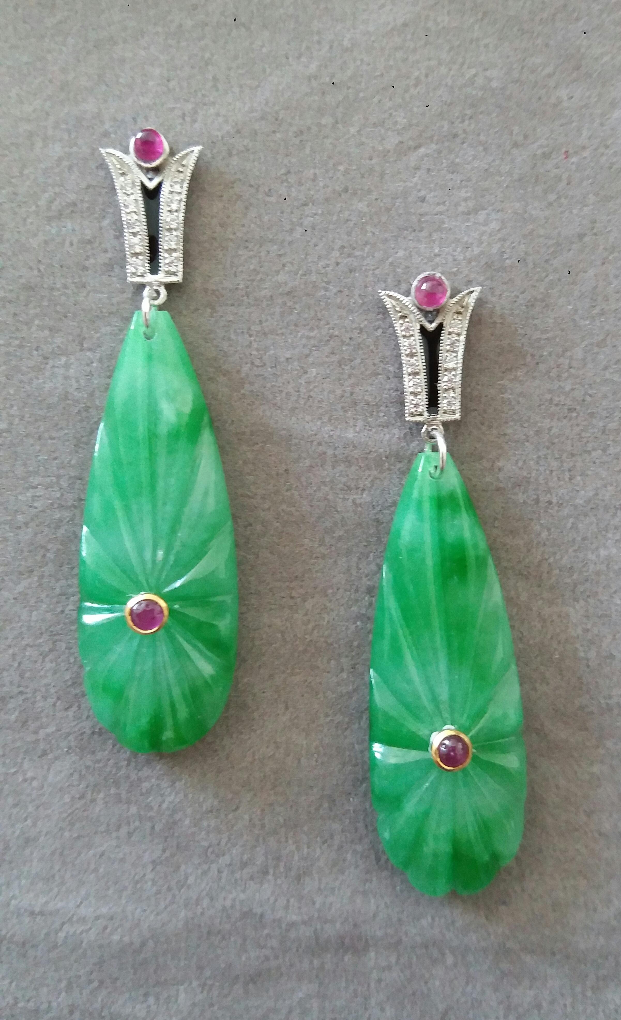 In these classic Art Deco Style earrings the tops are 2 parts  in 14 kt.white gold, 20 round full cut diamonds,small round ruby cabs and black enamel ,in the lower parts we have 2 Burma Jade engraved  drops measuring 13 x 38 mm with 2 small ruby