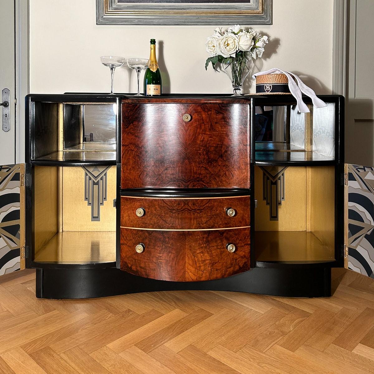 This substantial solid wood cocktail cabinet, crafted by an iconic British furniture maker, embodies the design aesthetics of the 1950s while exuding the distinctive style of the Art Deco period. Its curvaceous and glamorous silhouette is