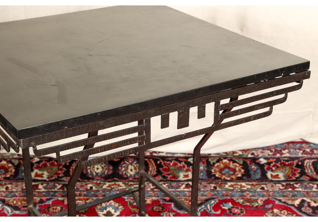 Stylish Art Deco style Center Table with Iron base. A black melamine top mounted on a cast iron base with slatted geometric patterned frieze panels. Raise on tall angular legs with out-swept bent feet and stretchers on all sides. Said to be a