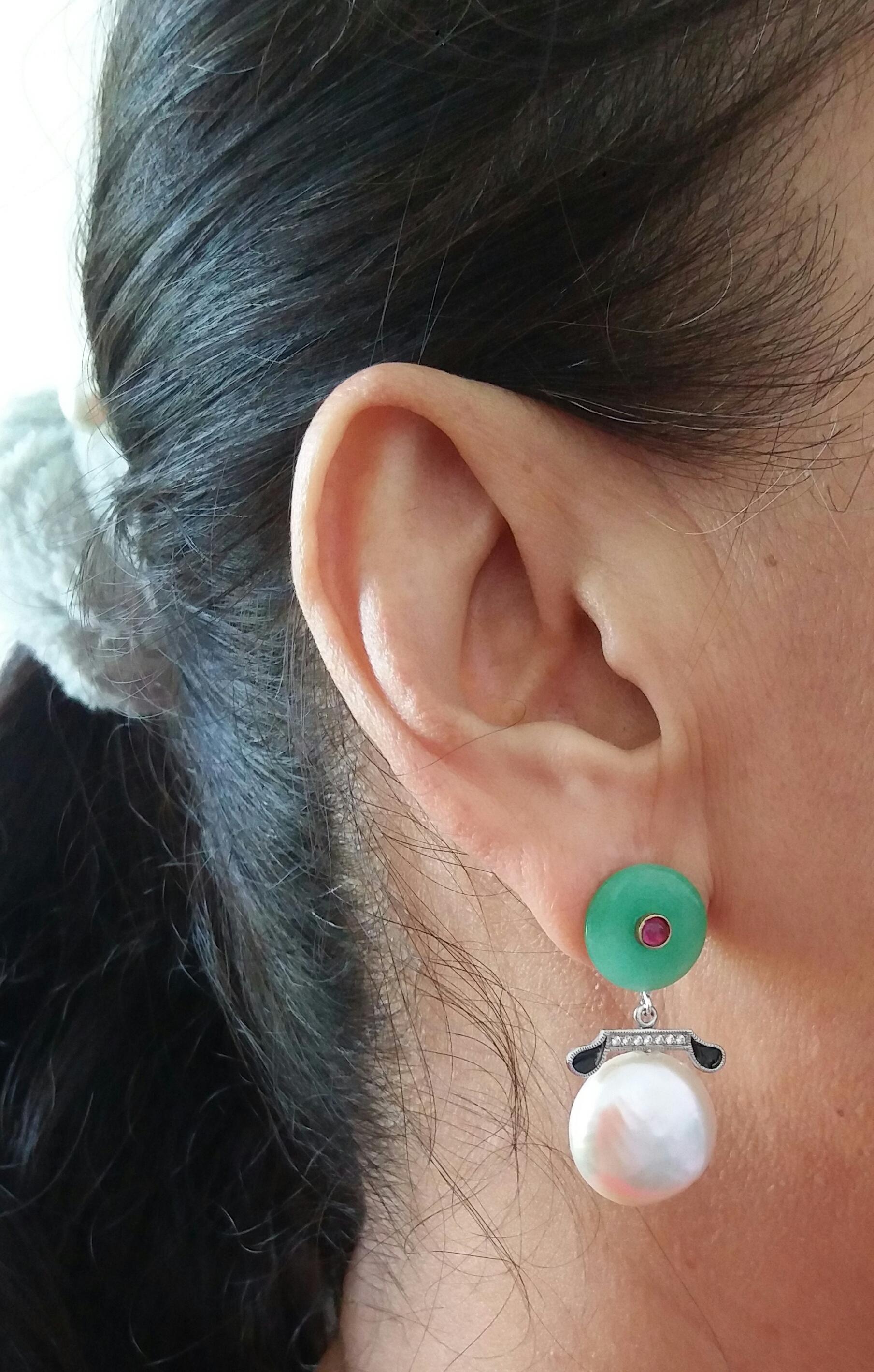 In these simple but elegant earrings we have the tops with 2 round Jade discs of 13 mm in diameter with small rubies cabochons in the center,middle parts in white gold, 14 full cut round diamonds and black enamel, the bottom parts are composed of 2 