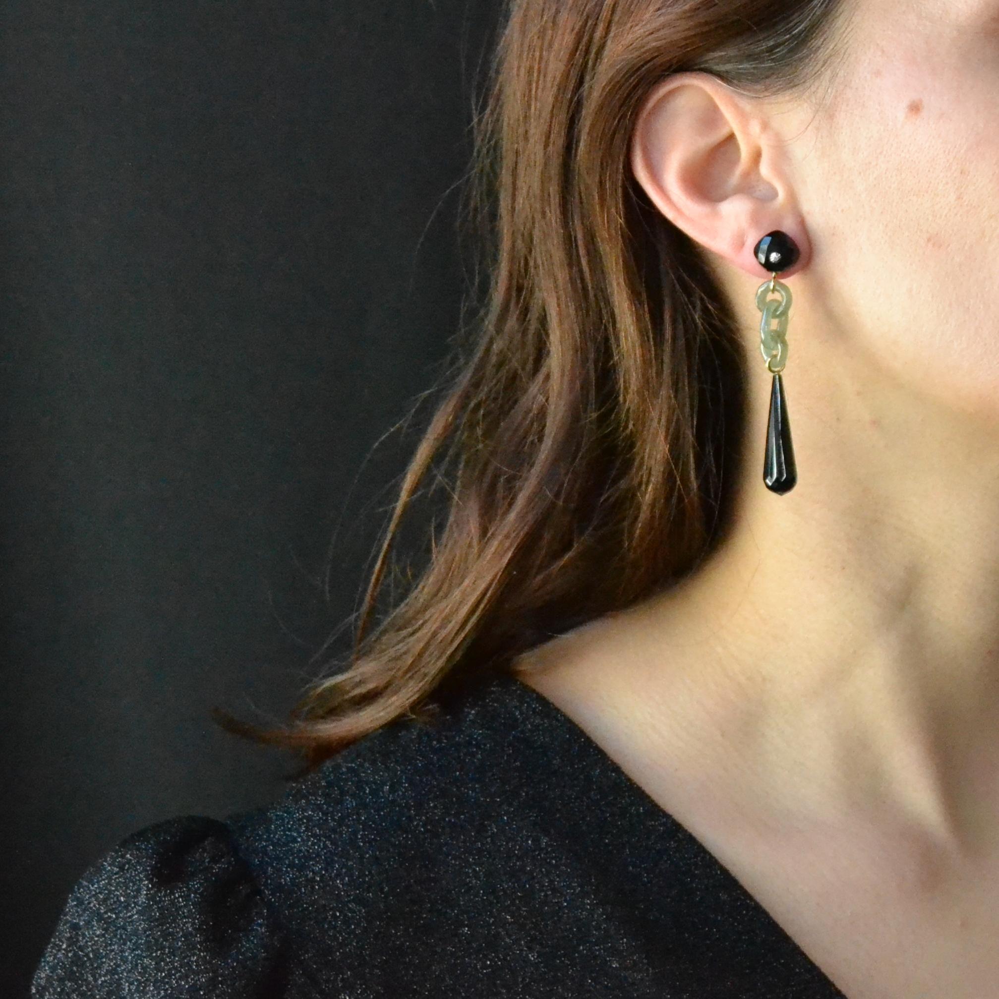 For pierced ears.
Pair of art deco style earrings, each one is made of a cushion- cut faceted onyx set in its center with a diamond. It holds green jade rings in tassel, and ends with a long drop of faceted onyx. The hanging system is