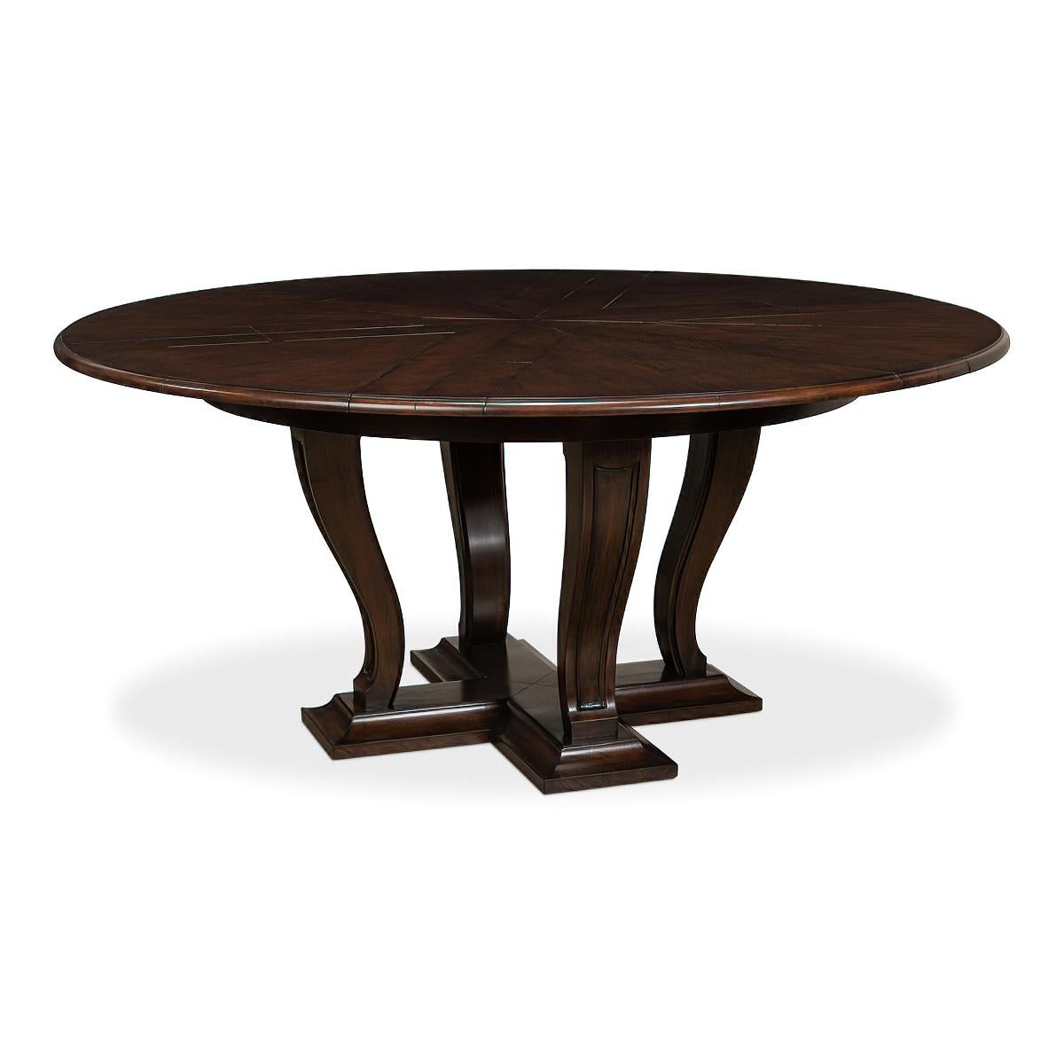 A 70-inch round Art Deco Style dining table on a transitional styled base consisting of tapered serpentine curved legs that have been carved with an inset panel design. They sit on a platform base that has been framed with a bold cove shape. The top