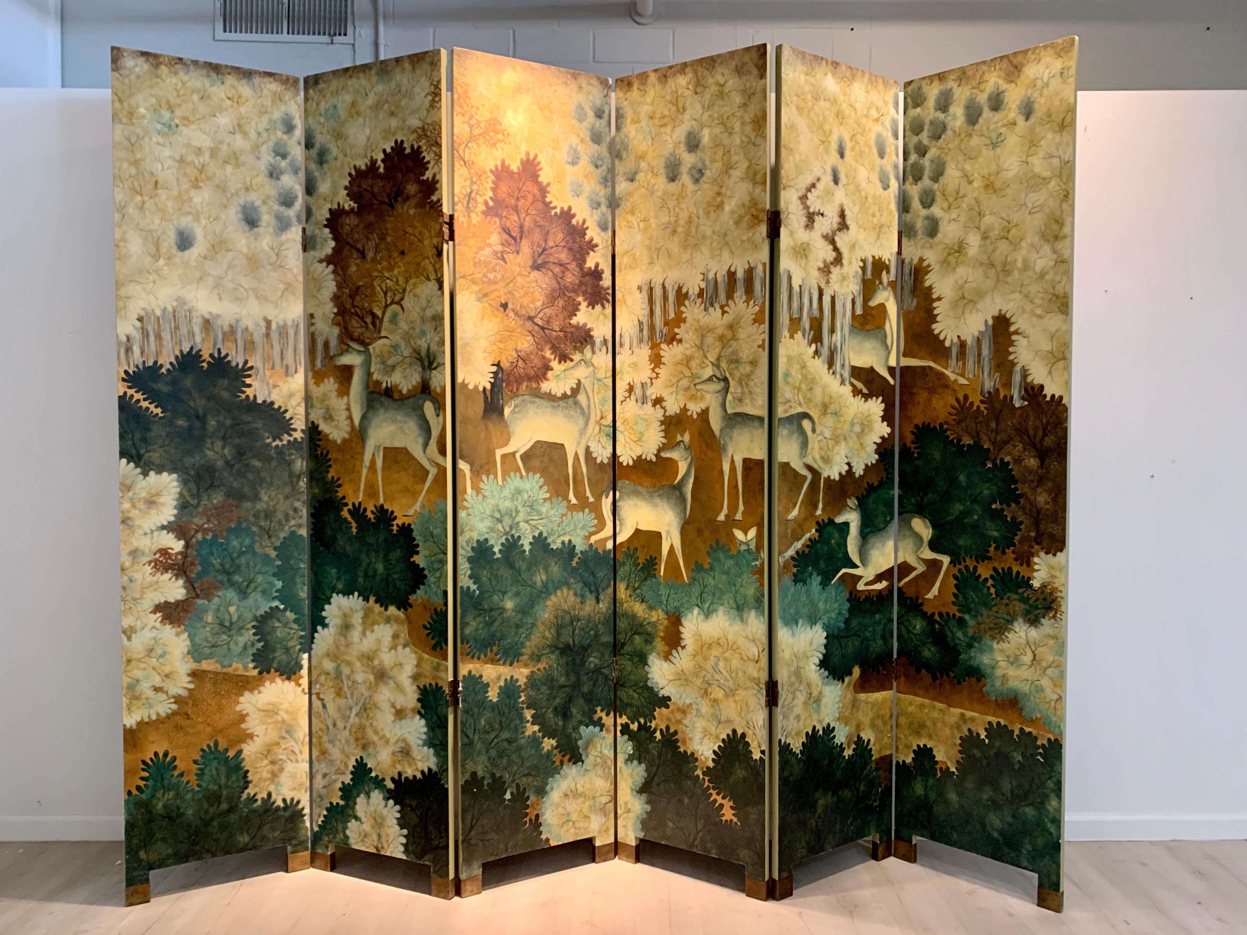 A spectacular large Art Deco style lacquer painted wooden screen with images of deer in a forrest, in the styles of Jean Dunand and Pham Hau, late 20th century, circa 1980's. 

The magnificent tall, six paneled folding screen of hand painted lacquer