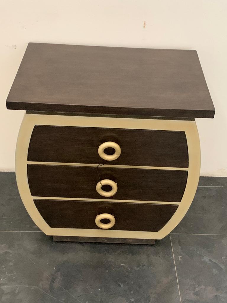 Kommode im Art-Déco-Stil von Lam Lee, 1990er Jahre. Holzstruktur mit abgerundeten Seiten; Korpus mit Schwammlackierung auf Blattmetall, Schubladen und Platte mit Schwammlackierung mit Streifeneffekt. Griffe aus Metall.

Die Verpackung mit