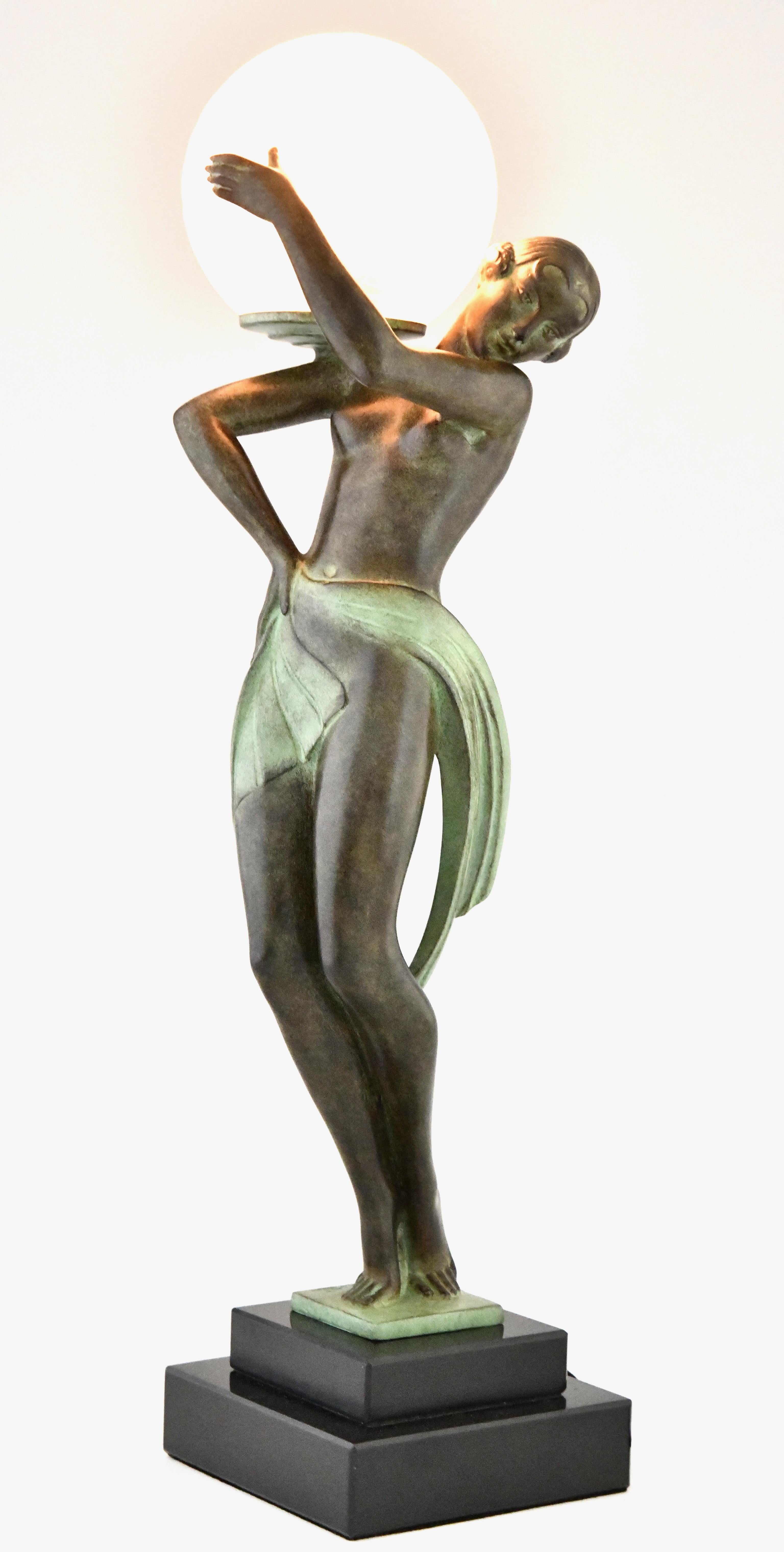 Lampe de style Deco Style danseuse avec boule FARANDOLE par Fayral, pseudonyme de Pierre Le Faguays.
Avec le cachet de la fonderie Max Le Verrier. 
Métal d'art patiné sur une base en marbre noir. Globe en verre. 
Design/One 1930. 
Distribution