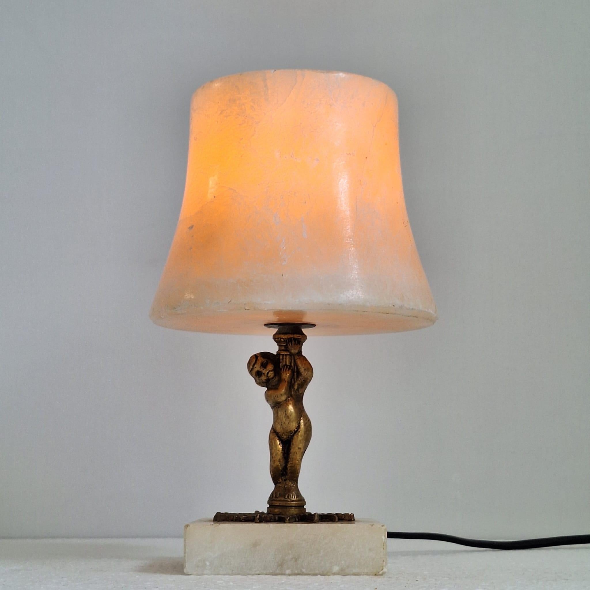 Preciosa lámpara de estilo Art Déco realizada en alabastro y bronce, que representa un querubín de bronce con una pantalla de alabastro. Algunos pequeños desconchones en los bordes del alabastro.