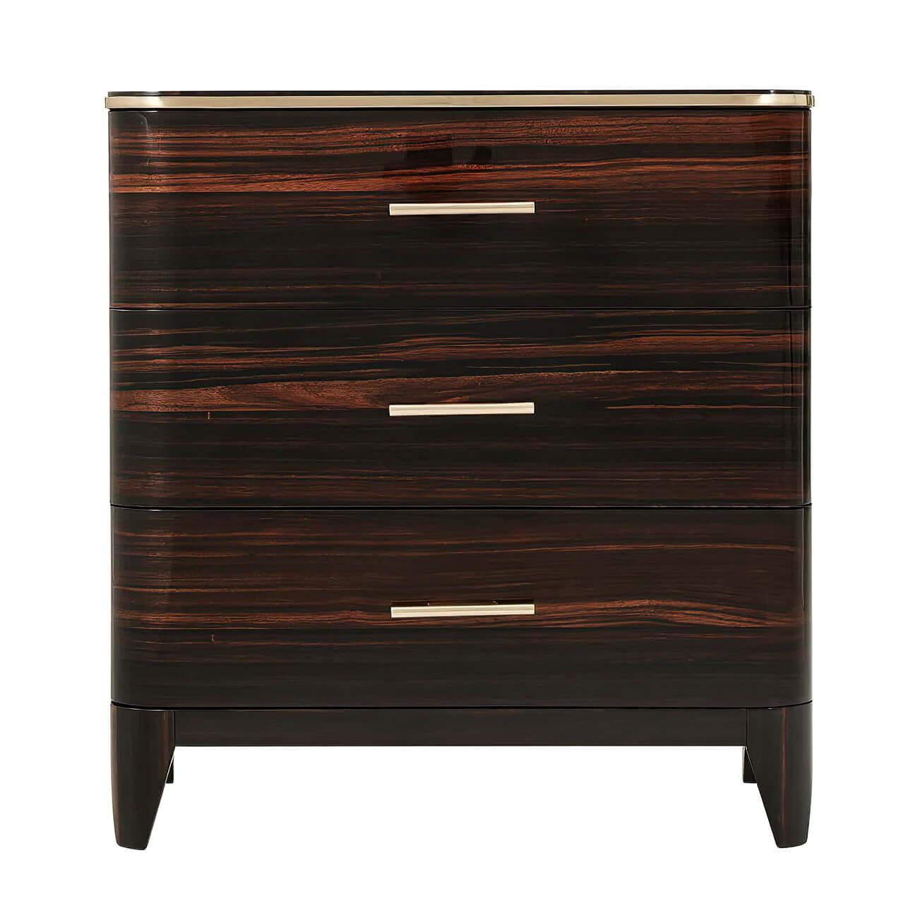 An Art Deco style nightstand inspired by 1930s luxury. This three-drawer chest with a rounded edge top with polished nickel trim, exotic Amara veneers with polished nickel finish handles, on tapering legs, with soft closing drawers.

Dimensions: