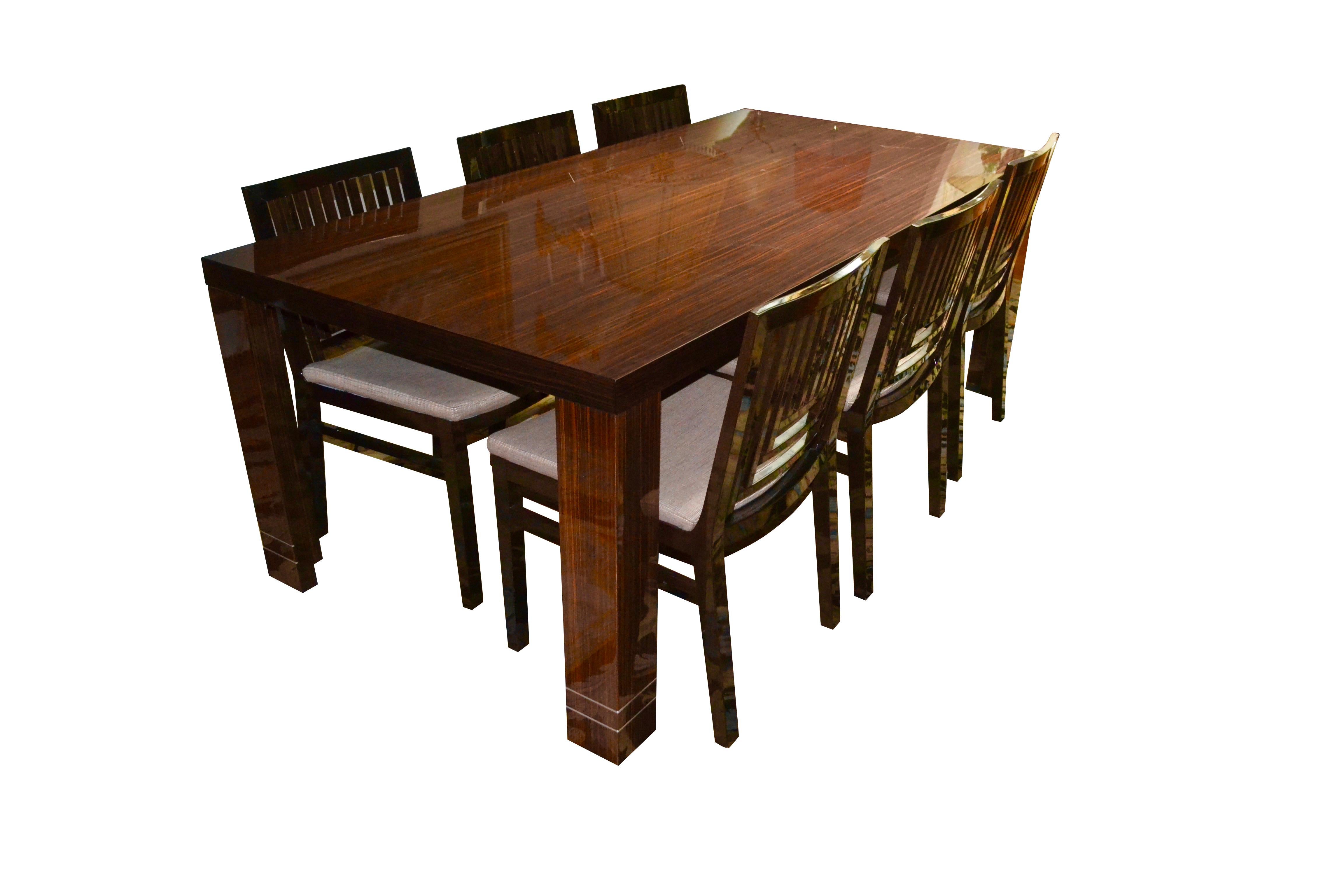A Classic French Art Deco style dining table together with eight matching chairs. The suite is entirely of veneered Macassar ebony in highly polished lacquer. Near the bottom of each leg are two decorative metal filets, the only decorative element