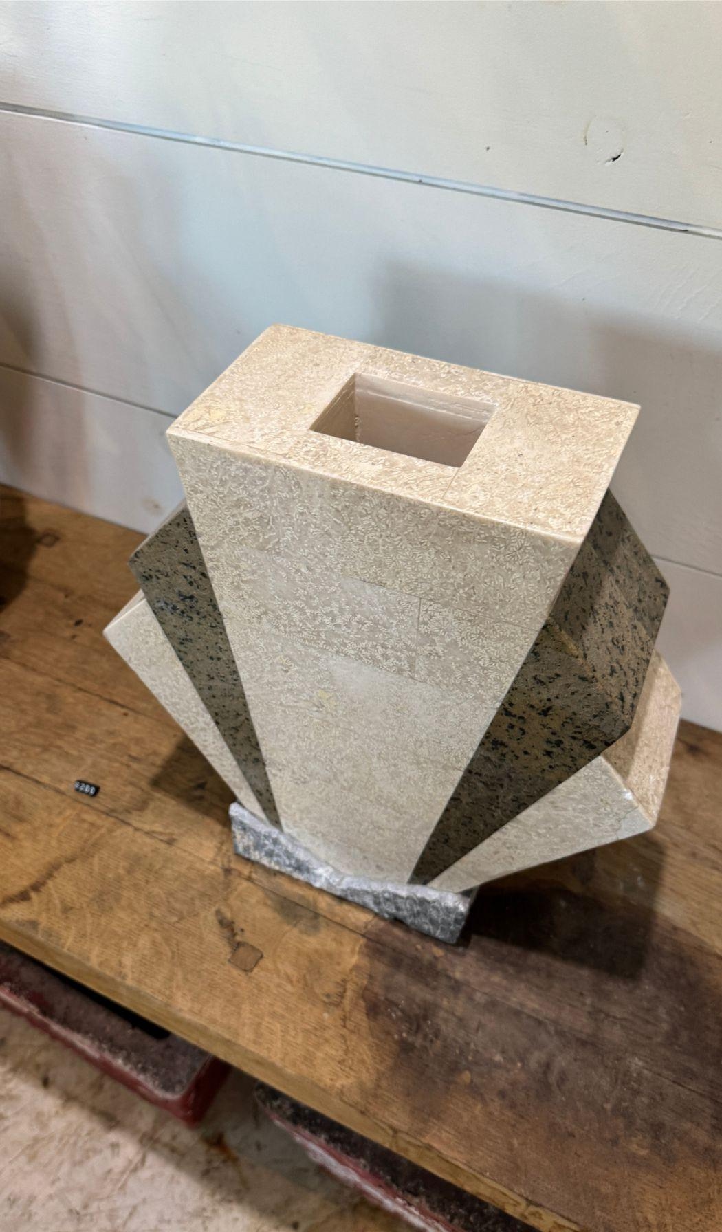 A striking Art Deco-inspired sculptural vase, masterfully crafted from fossil marble and dark granite. This geometric masterpiece features bold, fan-like faceted panels, creating a dynamic interplay of light and texture. The removable finial adds