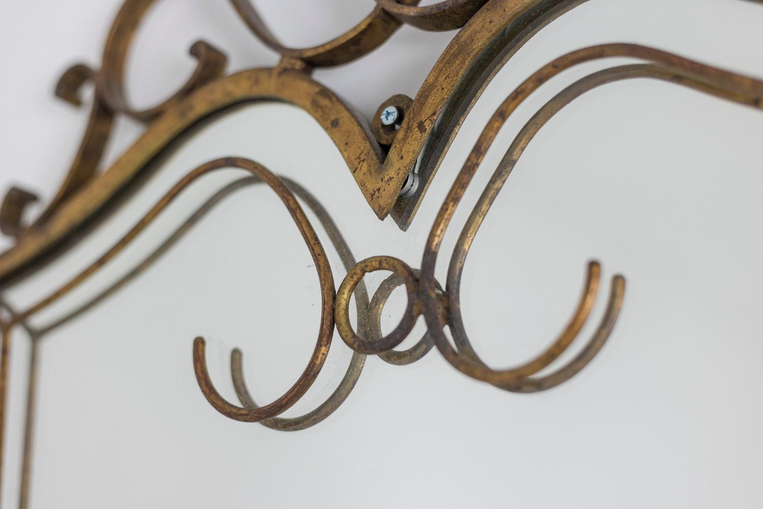 Art Deco style mirror in matte gilded iron, decorated with waves and a scalloped shape in the upper and lower part.

French work realized in the 1950s.