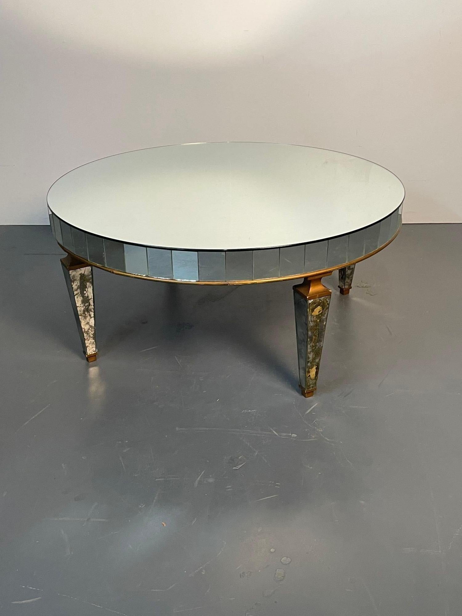 Art Deco style distressed mirrored circular coffee / cocktail / low table.
A sleek and stylish coffee or cocktail table of circular form. Having mirrored legs on all sides frames in a gilt wood border with matching top. The apron of micromosaic