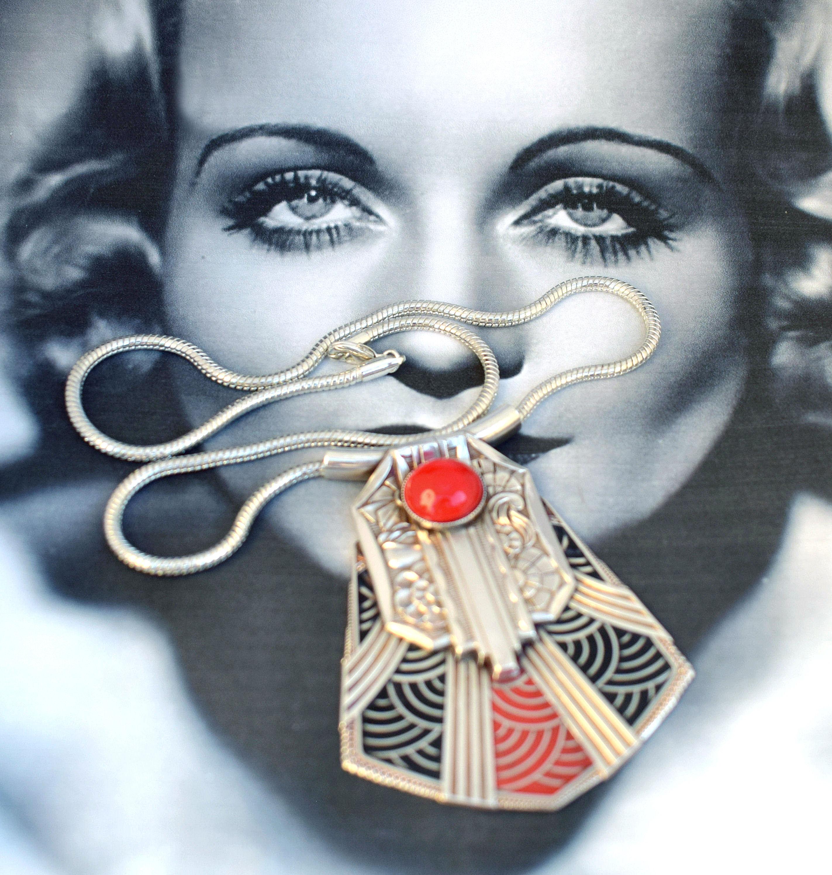 Favolosa collana modernista con i dettagli e l'artigianato più belli e raffinati: se ami l'Art Déco, questa dovrebbe farti battere il cuore. Presenta una decorazione a motivi geometrici in smalto rosso e nero su un pendente centrale che si trova su