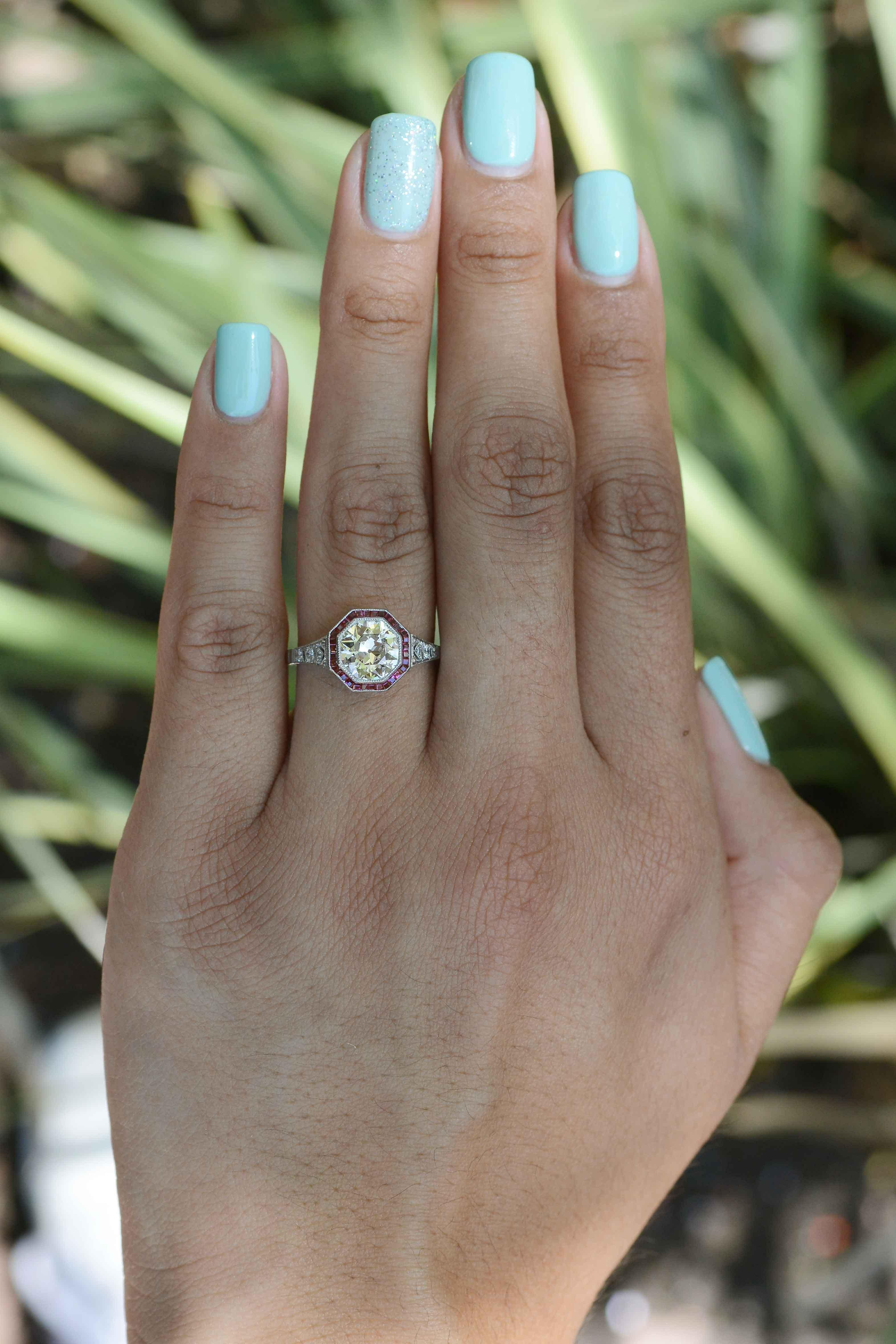 Octagonal Old European cut diamond and ruby engagement ring marries together sleek geometric lines with feminine filigree work popularized in the Art Deco era. The center hand cut diamond is beautifully haloed by 31 French cut rubies, all delicately