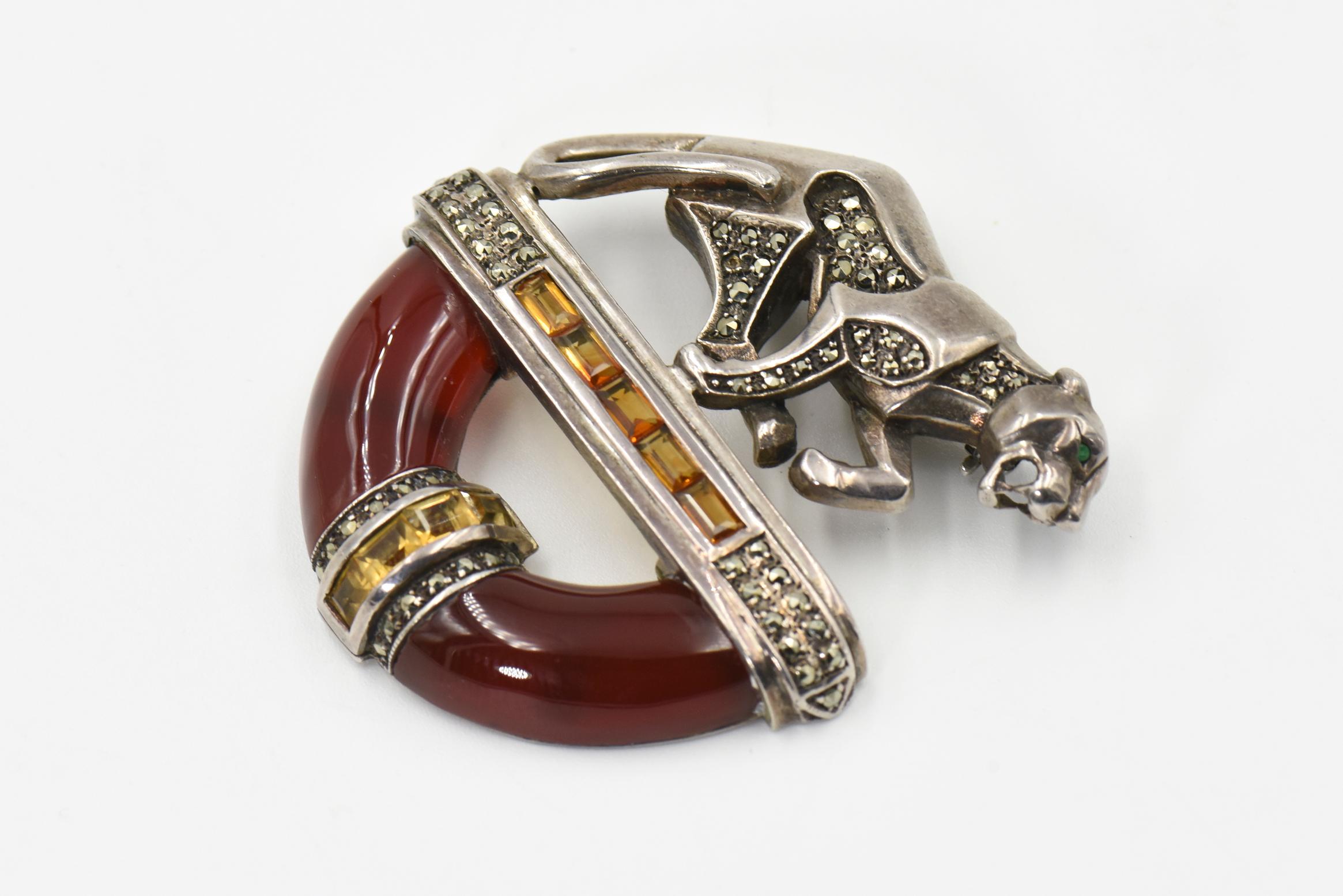 This beautiful panther brooch was inspired by the jewelry worn by the late Duchess of Windsor.  The brooch is sterling silver set with citrine, marcasite, carnelian and finished with an emerald eye.  