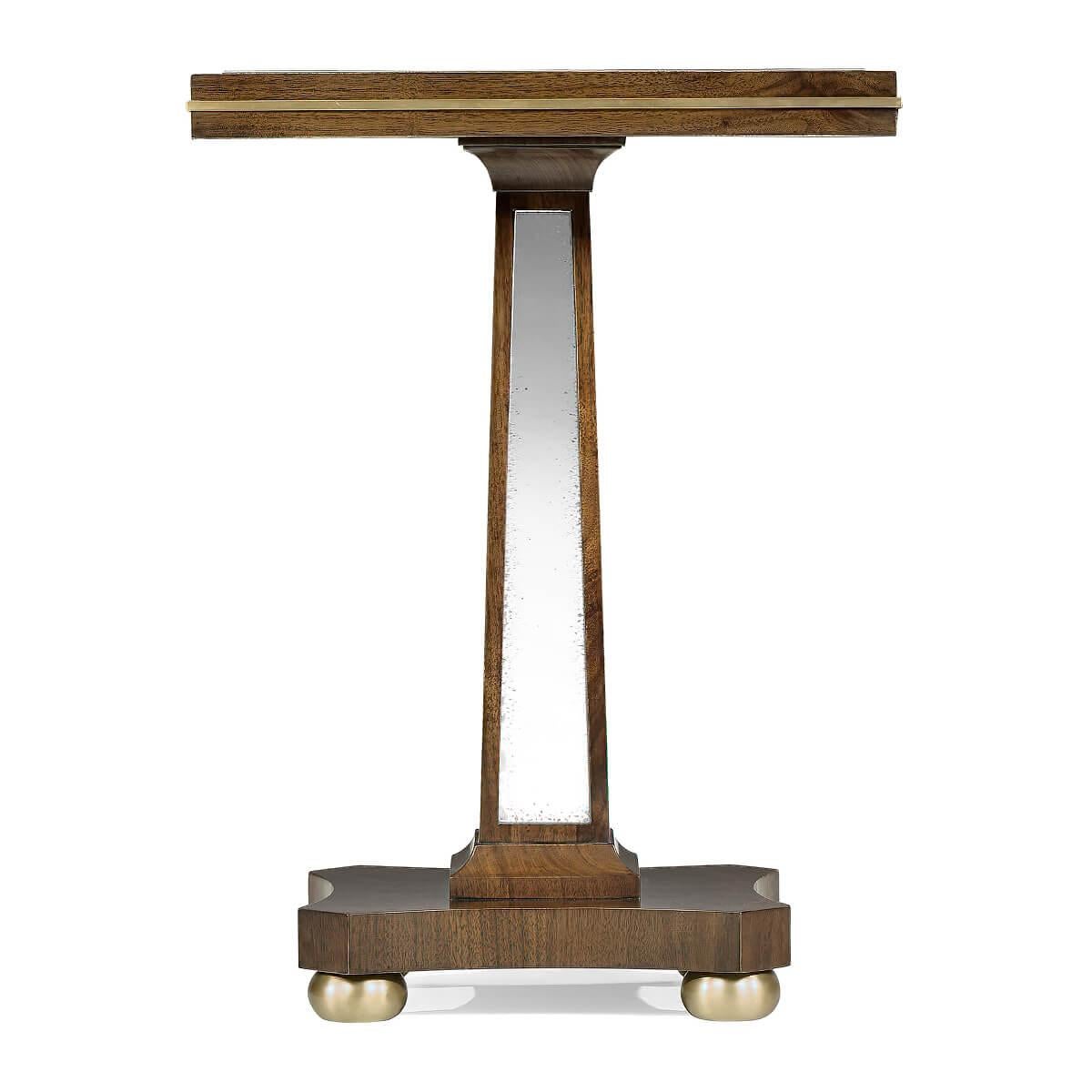 An Art Deco-inspired pedestal side table with an American walnut frame, antiqued mirror top, and panels pedestal sides with brass trim and hardware.

Dimensions: 17 1/8