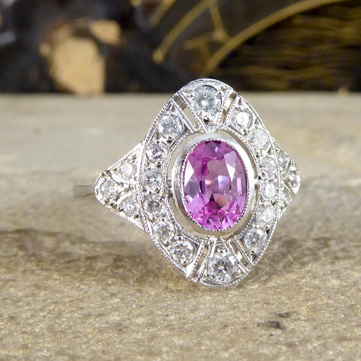 The design of this ring has been inspired from the classic Art Deco period, however has been crafted recently. Modelled in Platinum, the design features a beautiful and bright oval cut Pink Sapphire weighing 0.90ct in the centre with a surround of