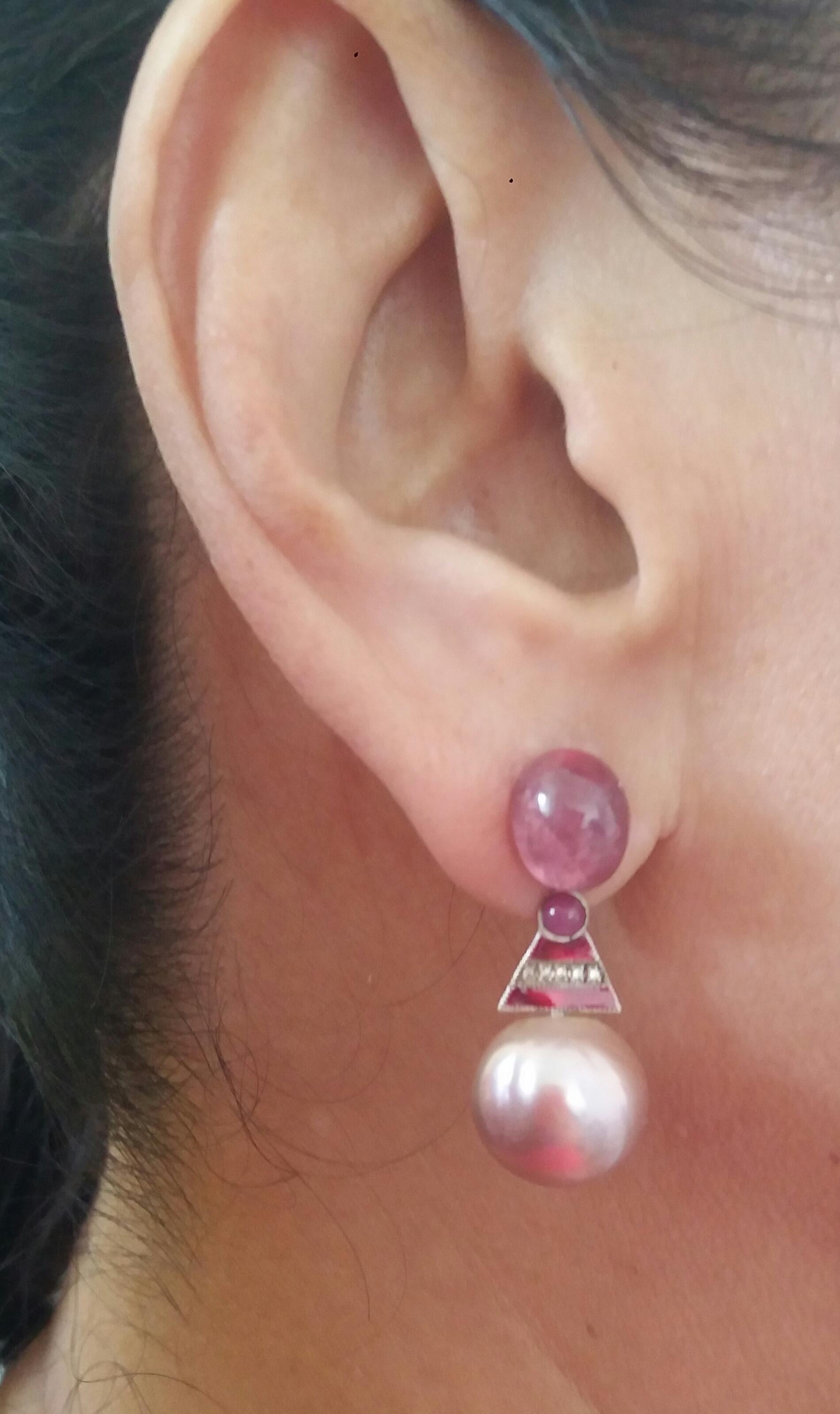Unique pair of earrings with on top a pair of oval Pink Tourmaline ( 8 x 10 mm) ,a central part composed of 2 triangle shape 14 kt. White Gold elements with 2 small round Ruby cabochons, 12 full cut round Diamonds and Red Enamel. In the bottom parts