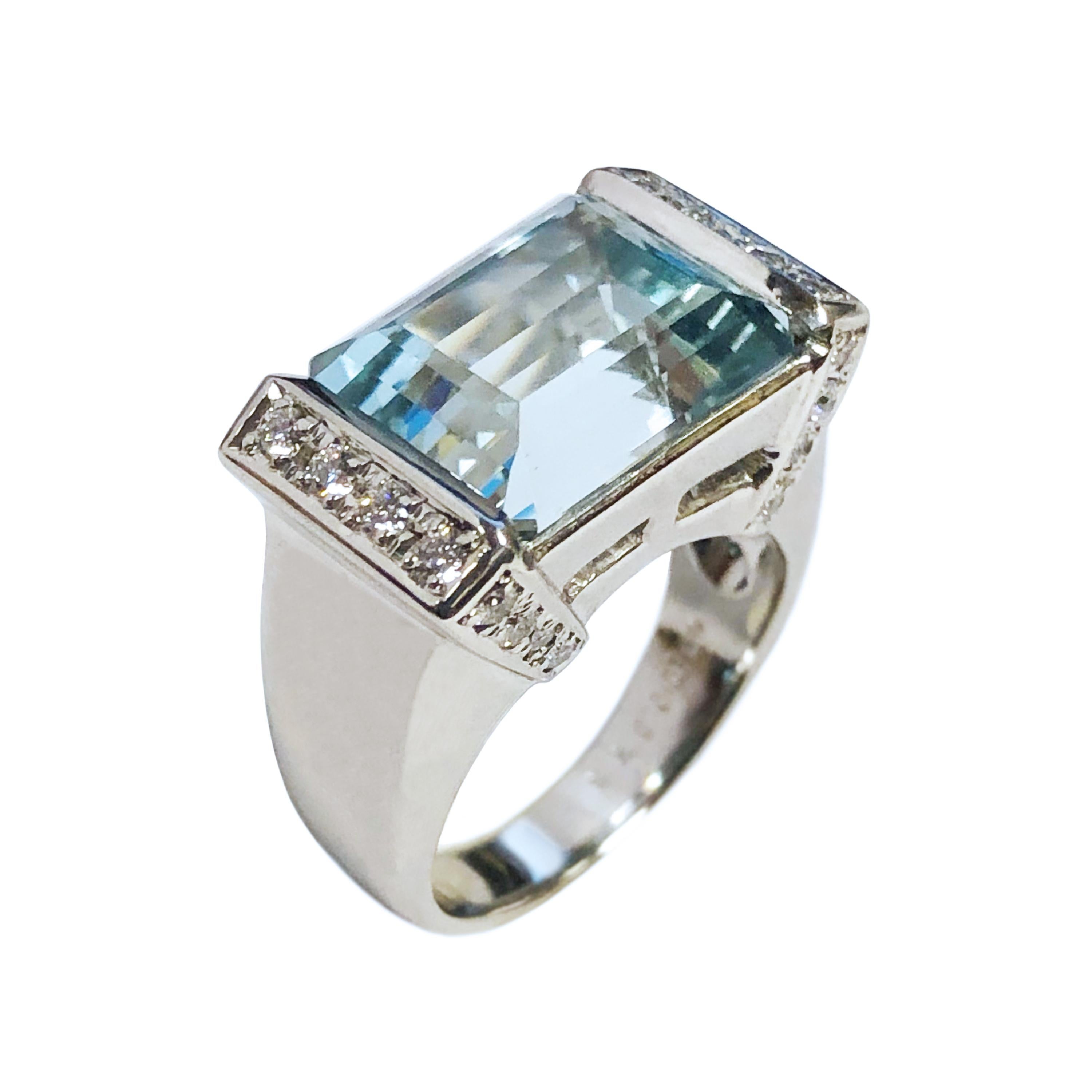 Circa 2010 Platinum Ring in an Art Deco style centrally set with a Fine Color step cut Aquamarine measuring 12 x 10 M.M. approximately 8 Carats and surrounded by Round Brilliant cut Diamonds totaling .75 Cart. The top of the ring measures 3/4 X 7