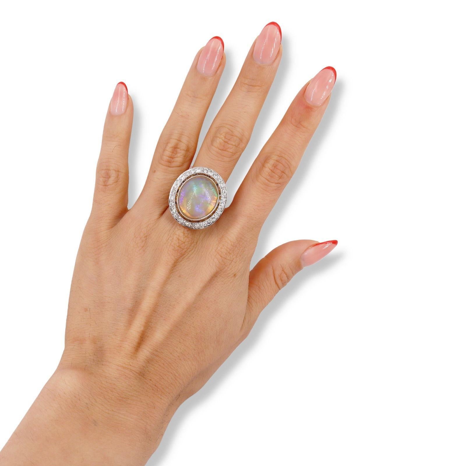 Deléitate con la elegancia de este Anillo de Cóctel de Platino, una pieza impresionante que captura la esencia del lujo y la sofisticación. En su centro yace un magnífico ópalo cabujón, con un peso aproximado de 30,0 quilates. El hipnotizador juego