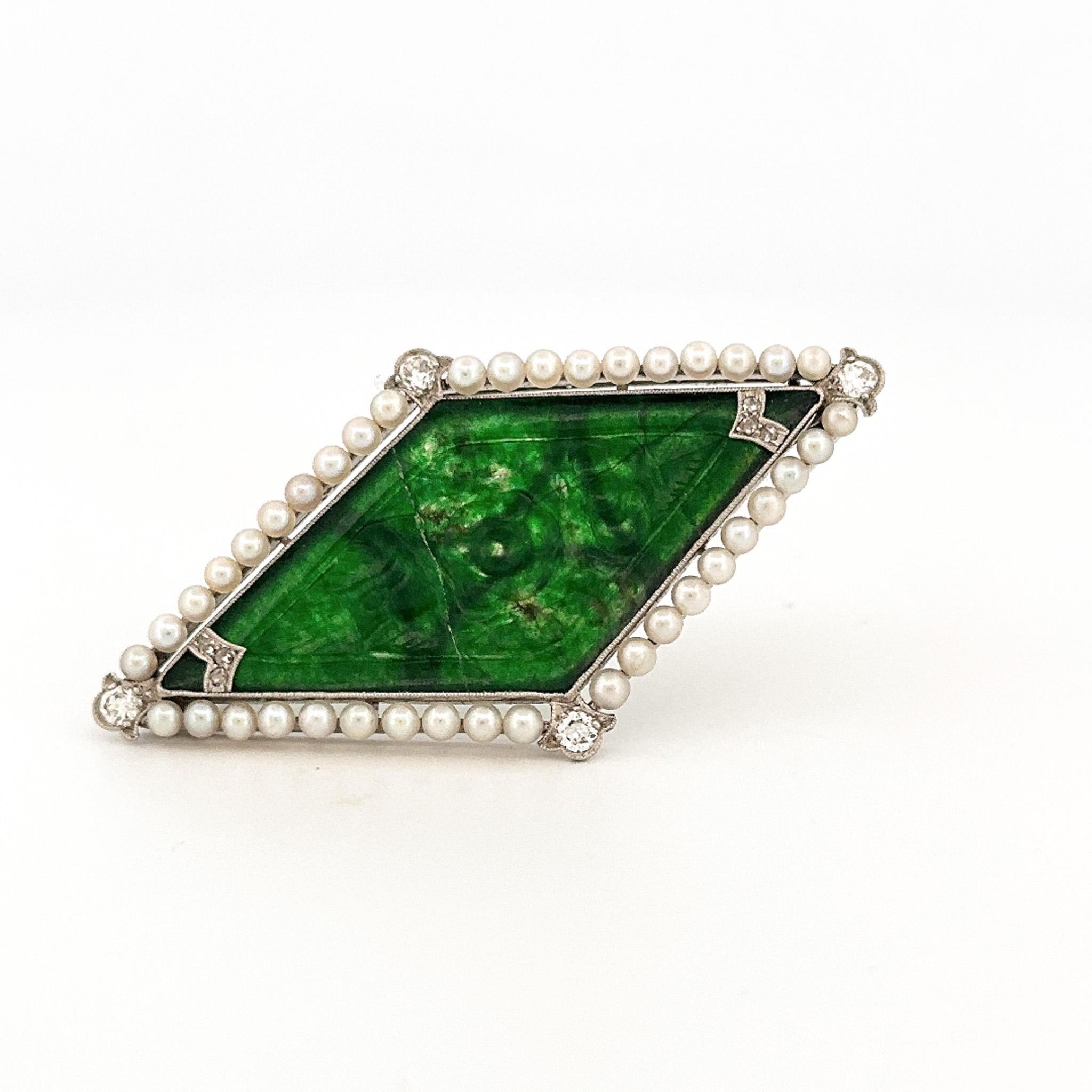 From the Eiseman Estate Jewelry Collection, this art deco inspired style platinum carved jade, pearl, and diamond pin. This pin is crafted with a carved jade slate surrounded by pearls with diamond accents. The jade is fractured from previous owner.
