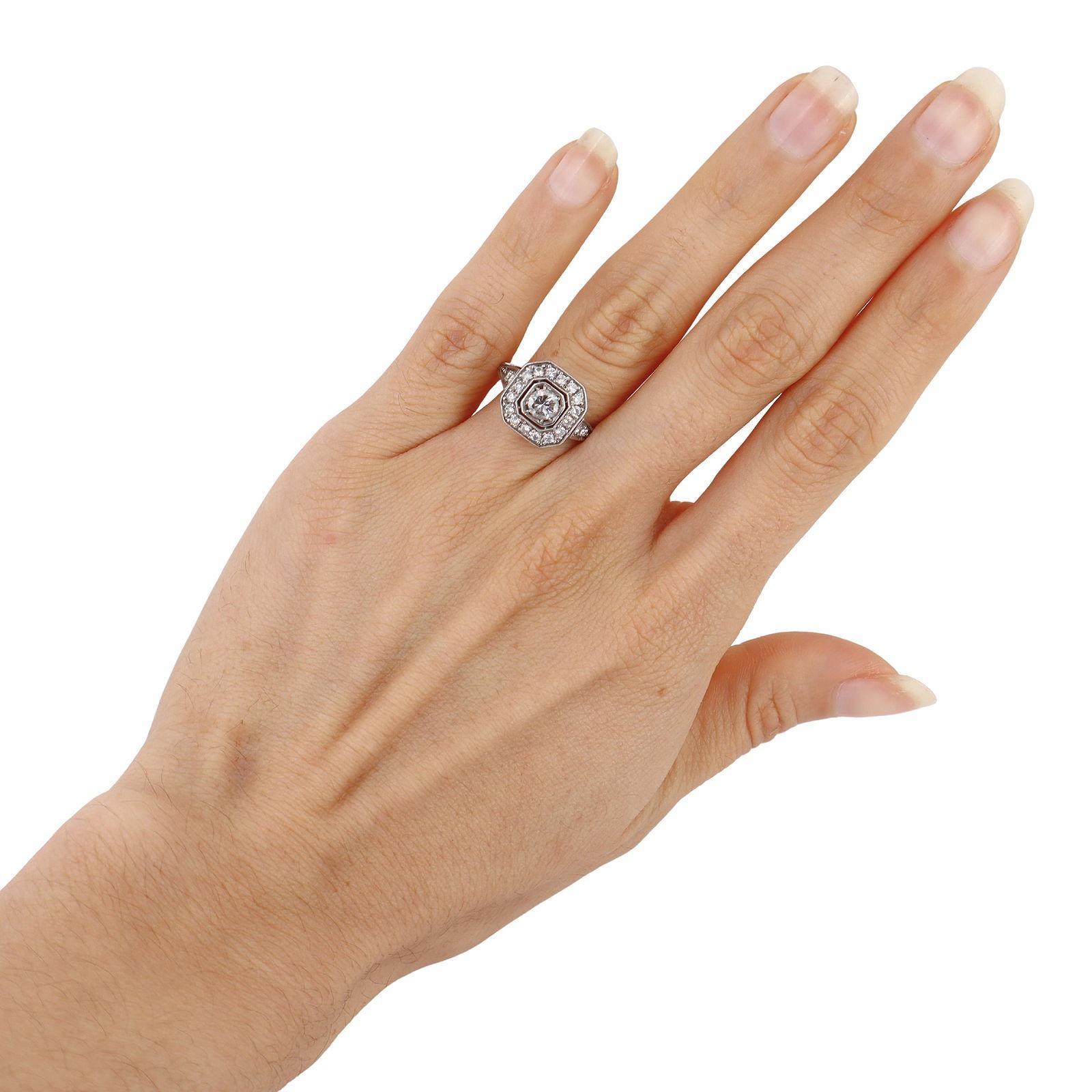 Questo elegante anello in stile Art Déco è sapientemente realizzato in platino e presenta uno scintillante diamante naturale centrale di circa 0,40 carati. La pietra centrale è circondata da un'aureola di 20 diamanti naturali, che insieme pesano