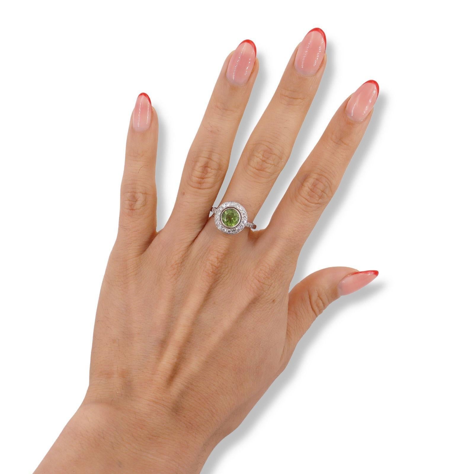 Ti presentiamo il nostro splendido anello Halo in platino, progettato per catturare l'essenza dell'eleganza e della raffinatezza. Al centro, un ipnotico Peridoto taglio rotondo di circa 1,40 carati brilla brillantemente, mostrando la sua vibrante