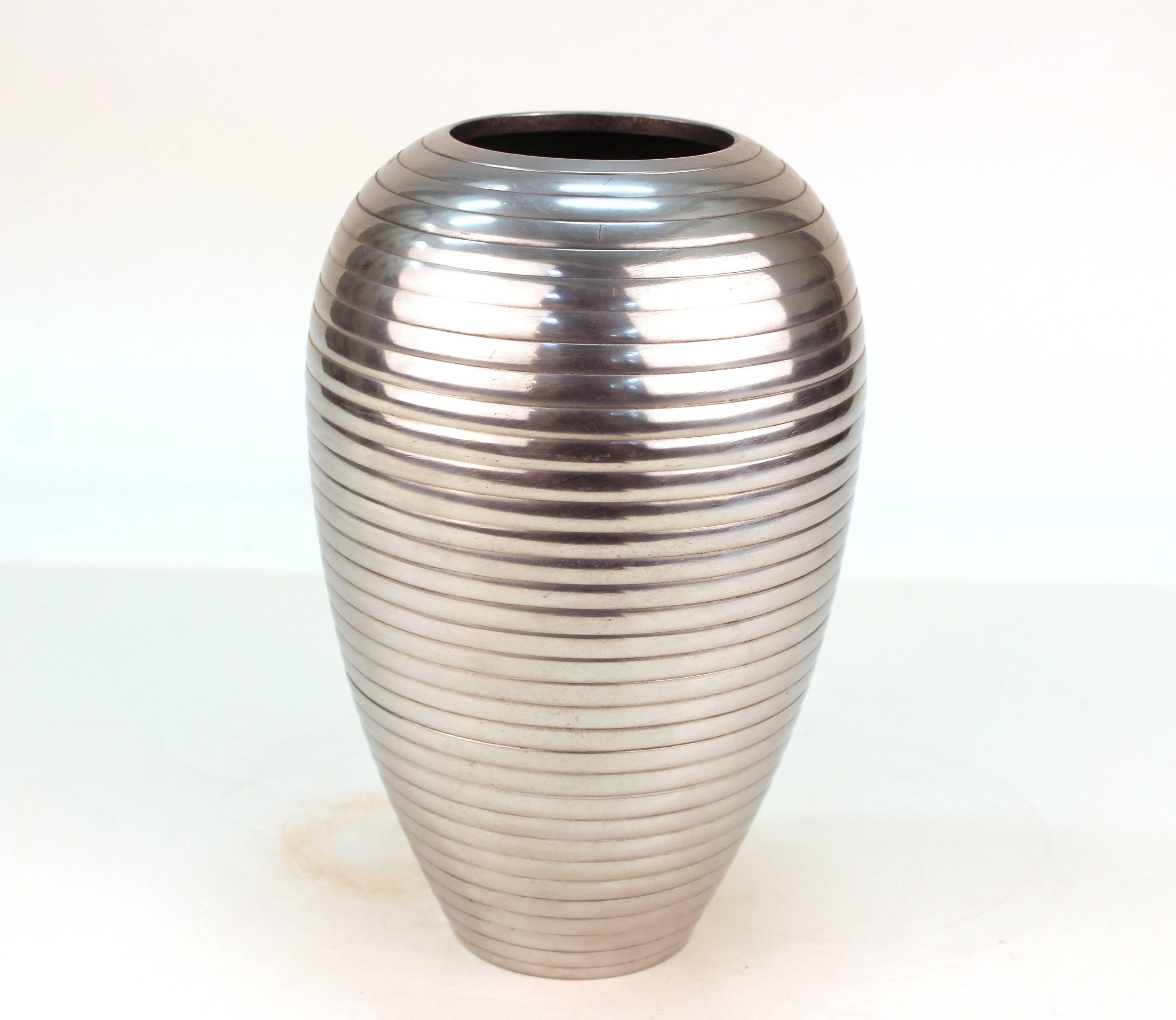 Art Deco style polished metal vase with a ribbed exterior. The piece has a few minor scratches on the bottom and is in good vintage condition.