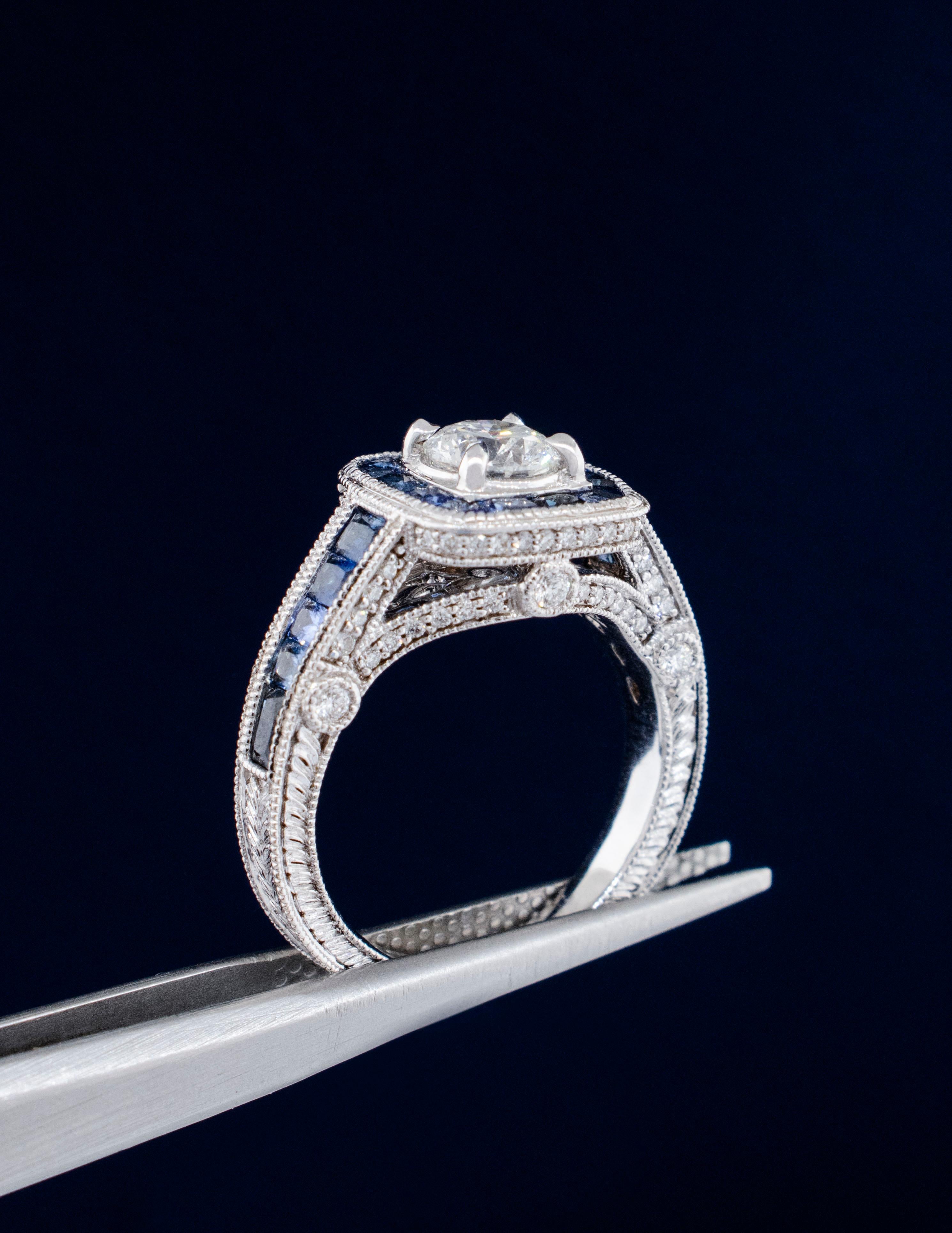 An Art Deco style ring made of 14K white gold with traditional engraving and milgrain accents. The center Diamond is a certified Rare & Forever Round Brilliant cut weighing .80 carats, grading F Color, SI2 Clarity, and Excellent Cut Grade. The